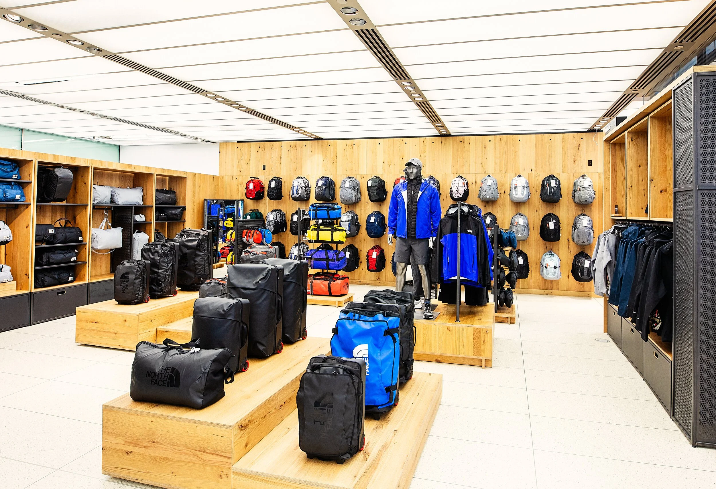 Store selling backpacks and outdoor gear, with shelves and display tables filled with various backpacks and duffel bags in different colors and sizes.