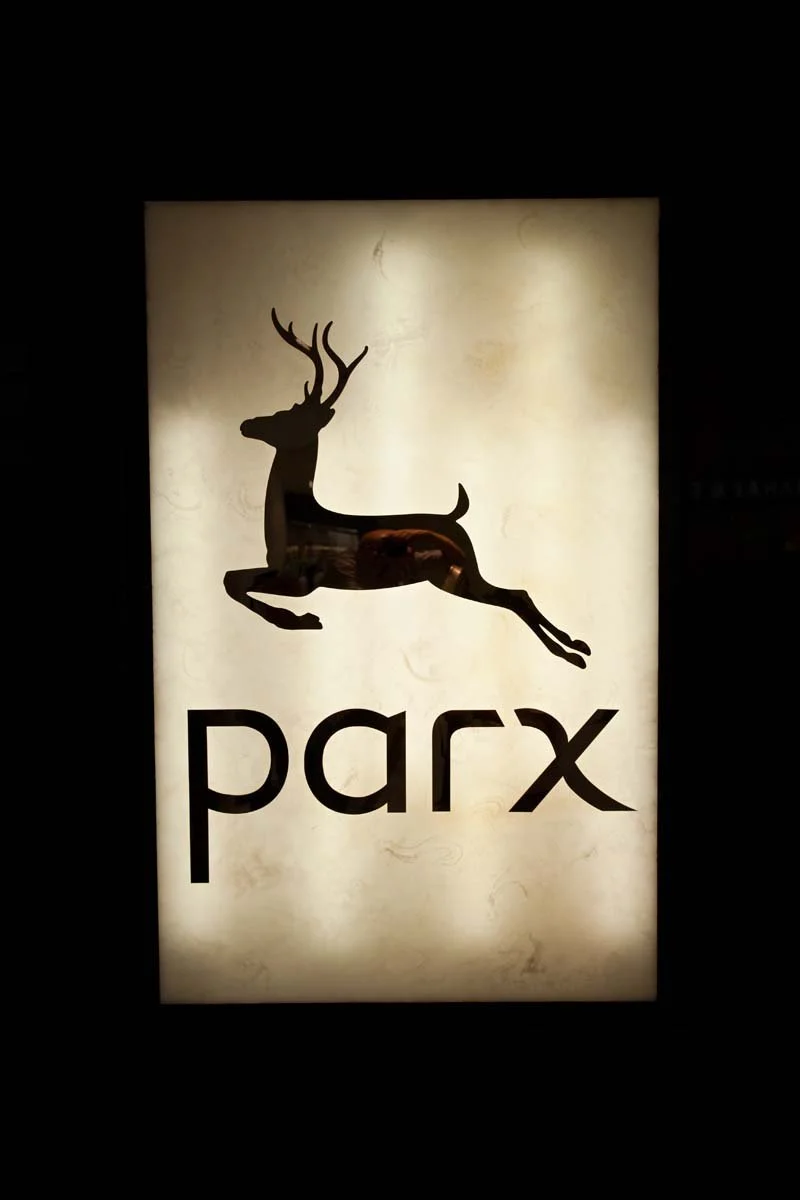 Backlit sign with a silhouette of a leaping deer above the word 'parx'