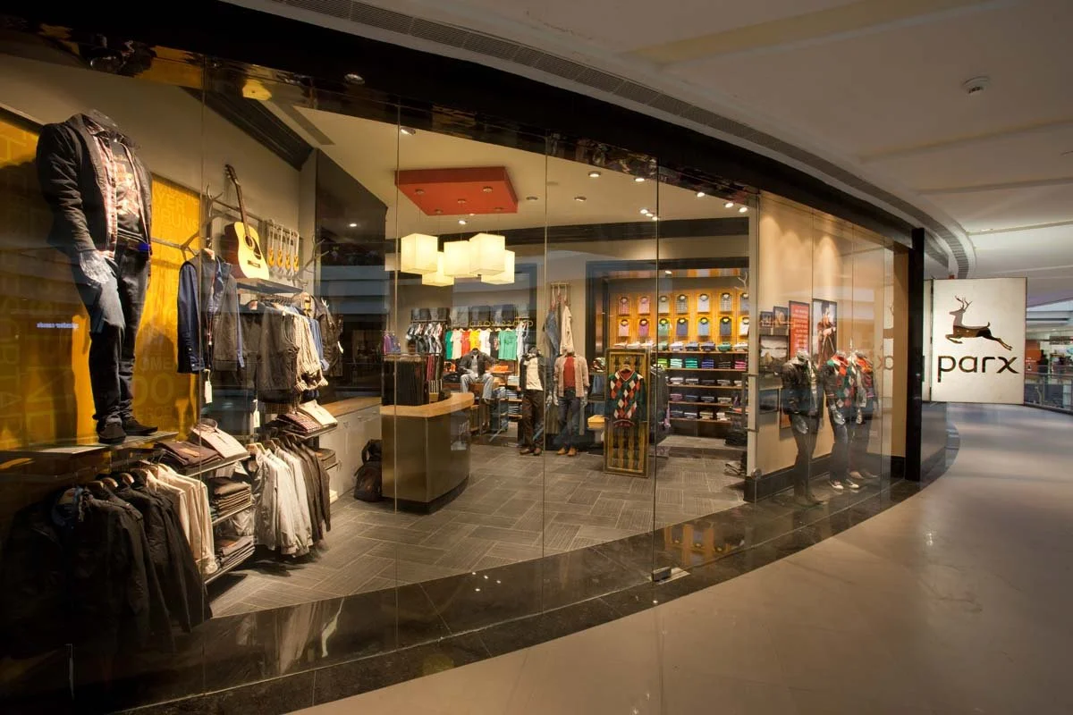 Clothing store called Parx with mannequins displaying jackets and shirts, interior shelves of folded clothes, and shoppers browsing inside.