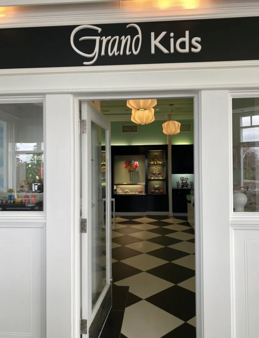 Entrance to Grand Kids, a store with a black and white checkered floor, white trim, and hanging lamps inside.