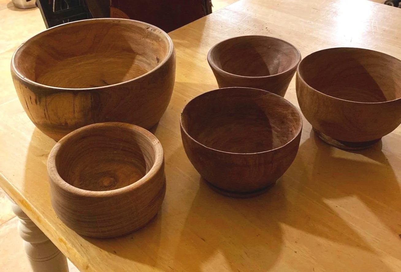 Six wooden bowls of various sizes arranged on a wooden table.