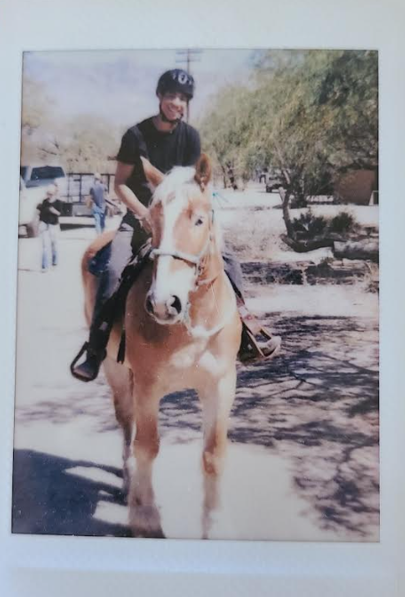 Person riding a light-colored horse outdoors on a sunny day. Darne, Ride Like Darne Scholarship