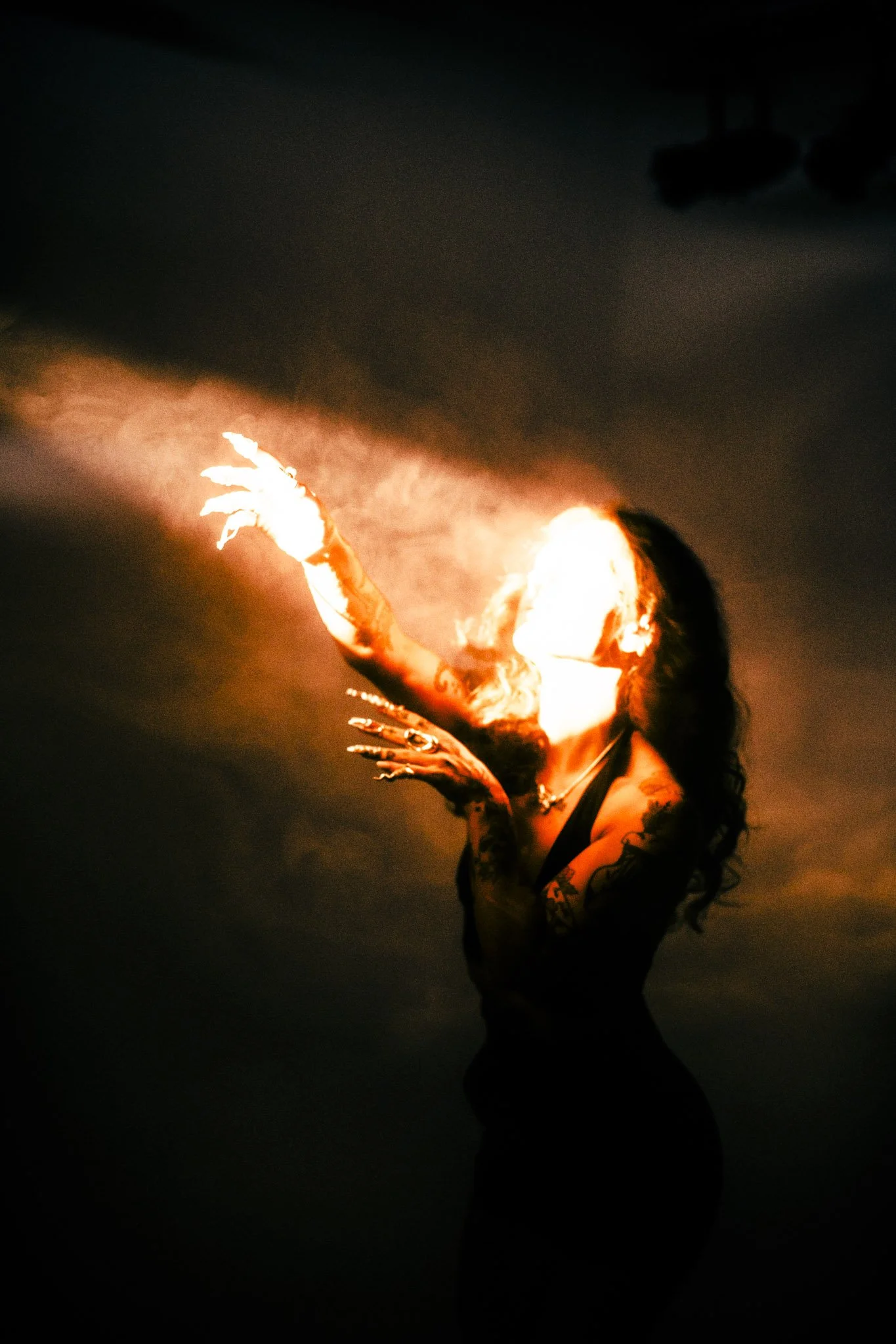 Person performing a fire dance at night, with flames creating a bright glow around them.