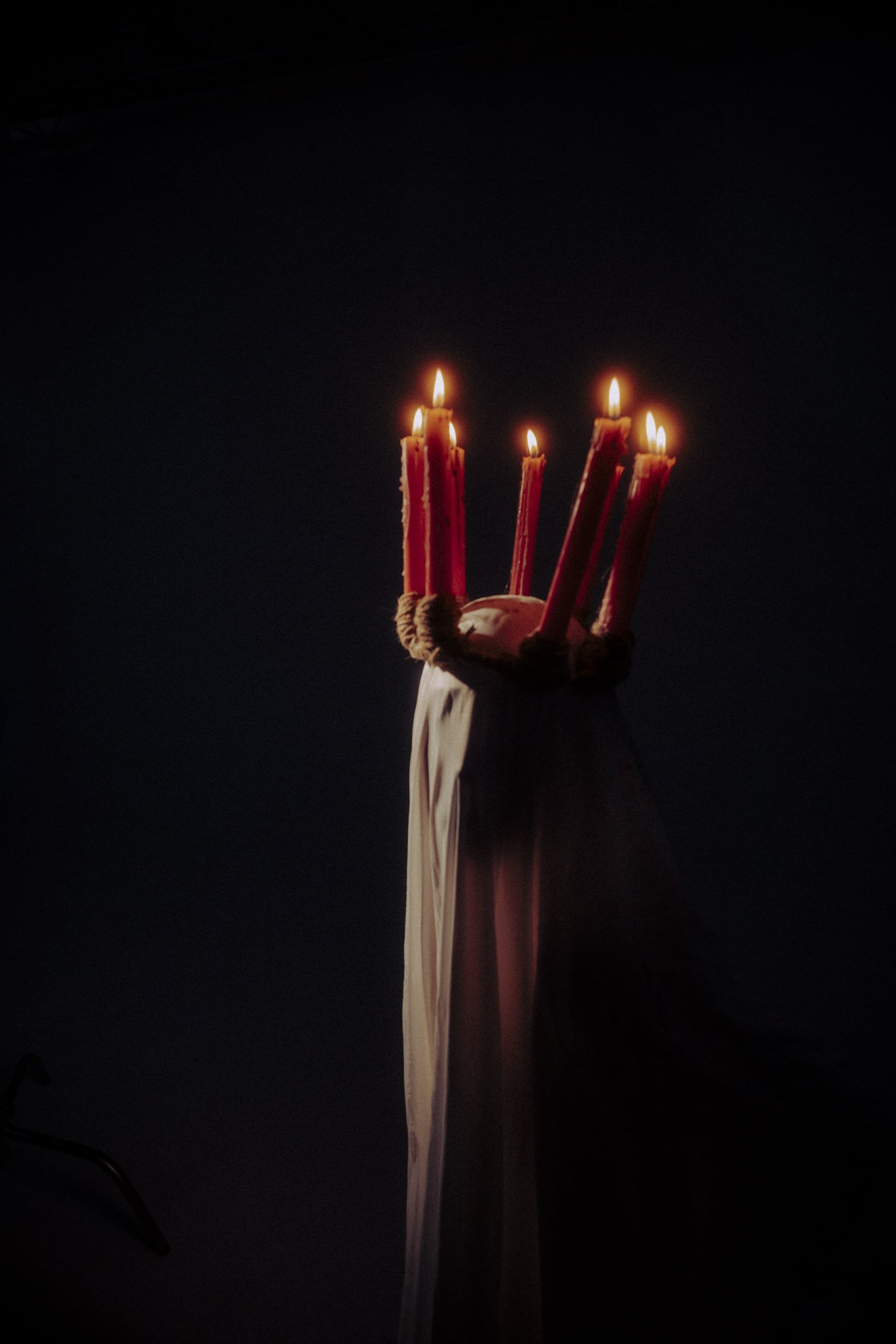 Five lit birthday candles on a cake against a dark background.