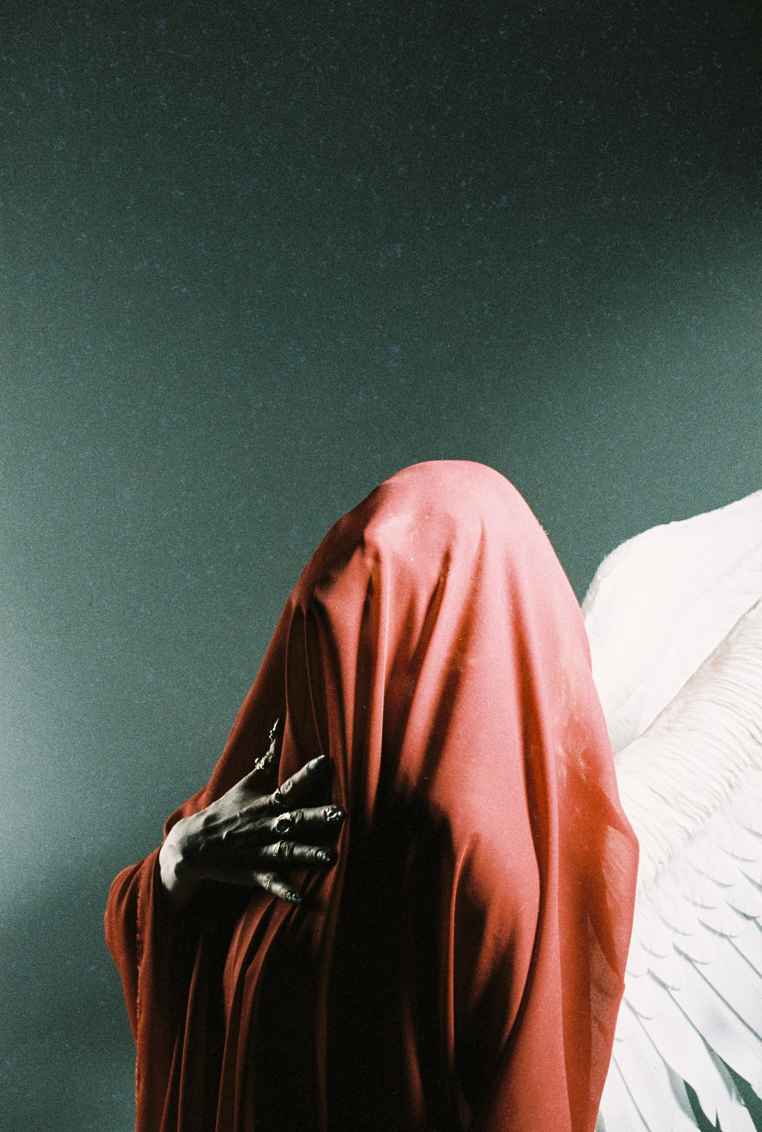 Person dressed in a red cloak with a black glove on hand, facing an abstract white wall with black lines, under a starry night sky.