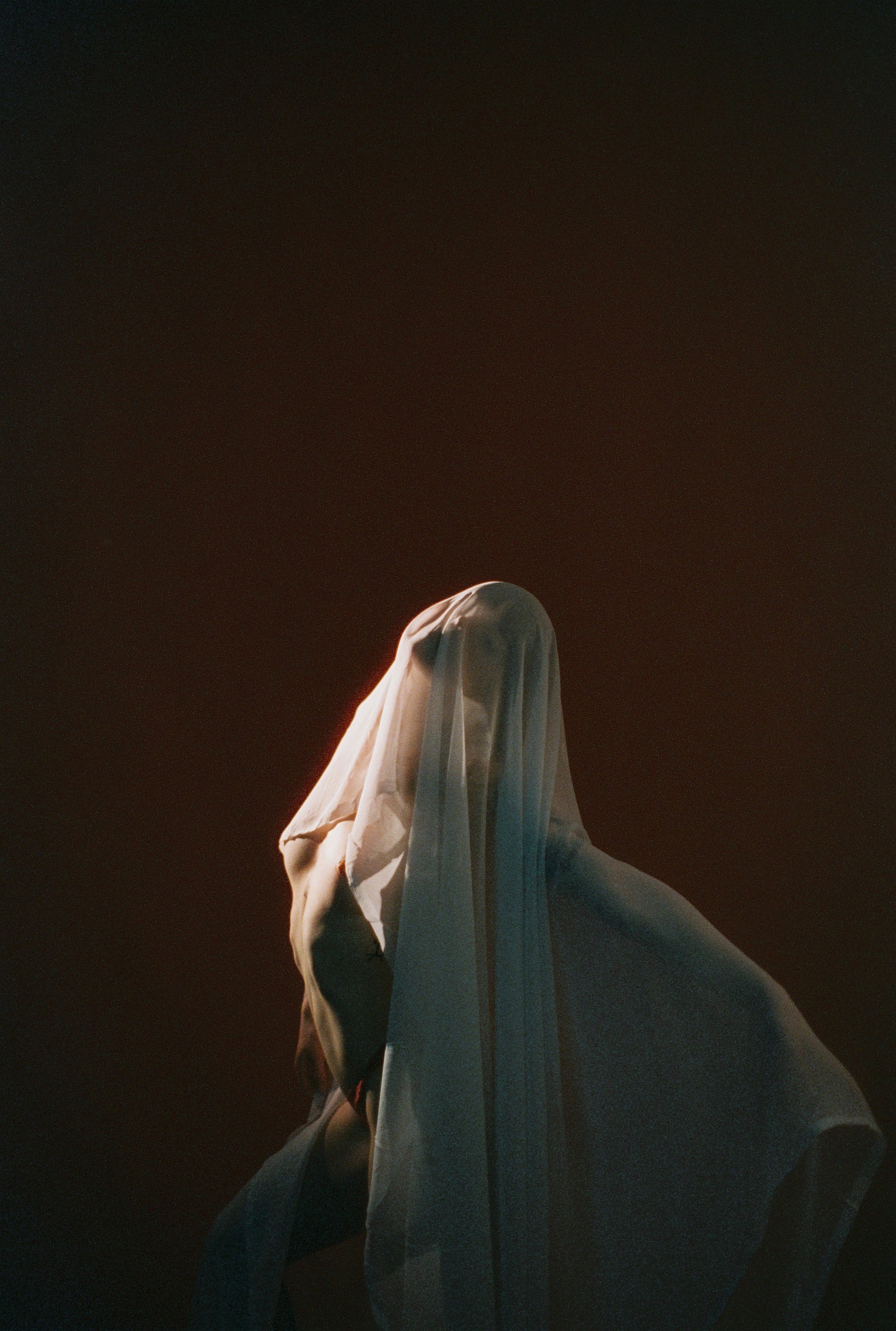 Statue of a woman in a flowing dress against a dark background, illuminated with soft lighting.