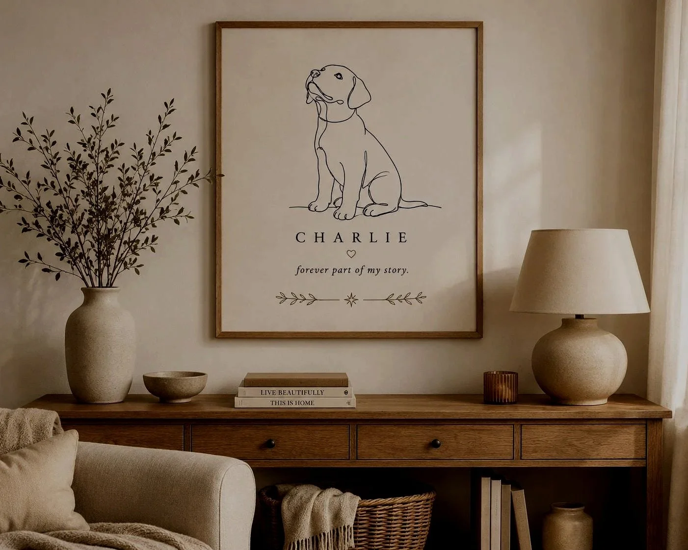 A neutral living room set up highligting a side draw minimally decorated. Above hangs a custom labrador portrait with the words, Charlie, forever part of my story.