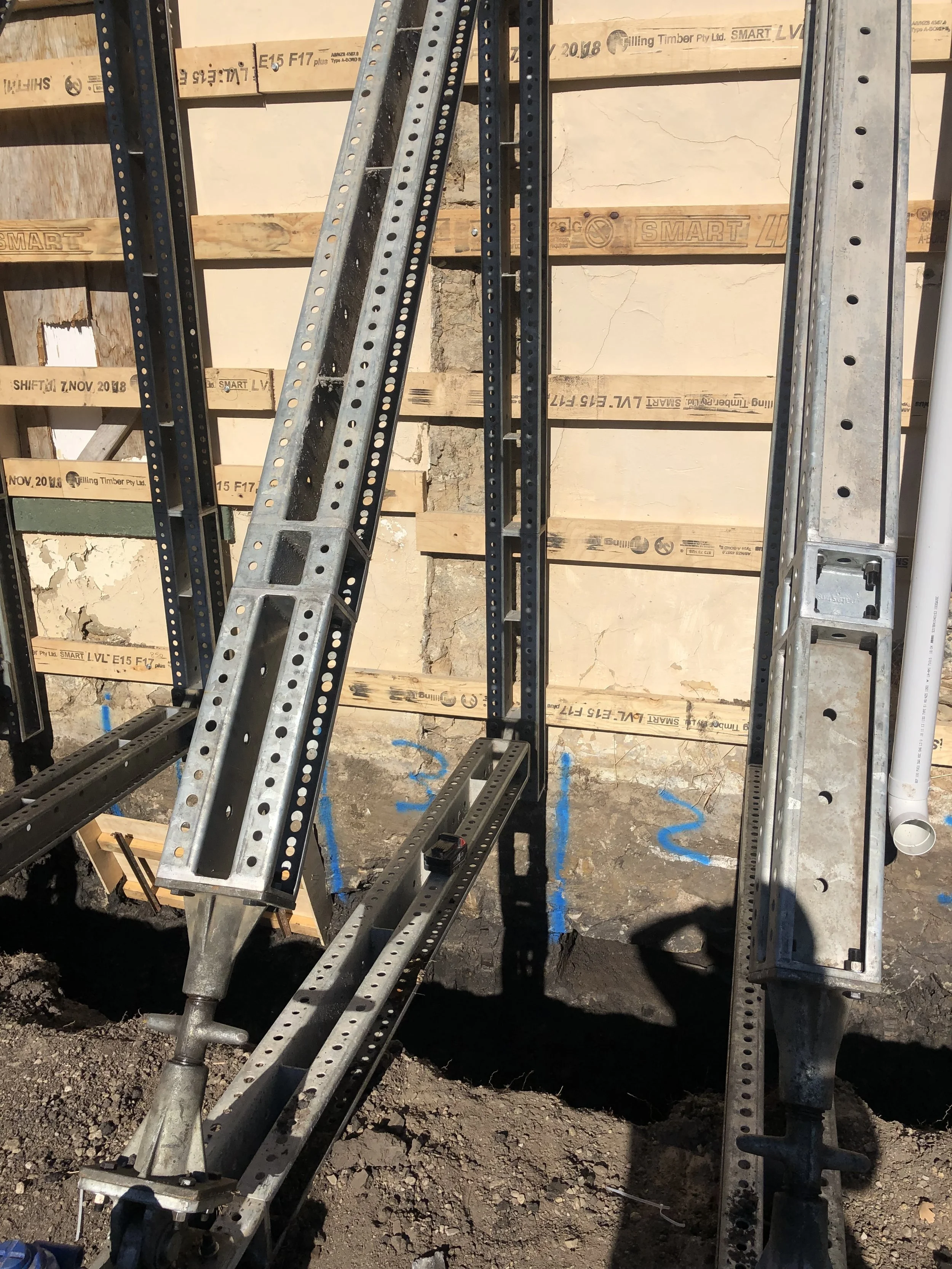 Steel support structure and scaffolding on a construction site with exposed concrete and dirt ground.