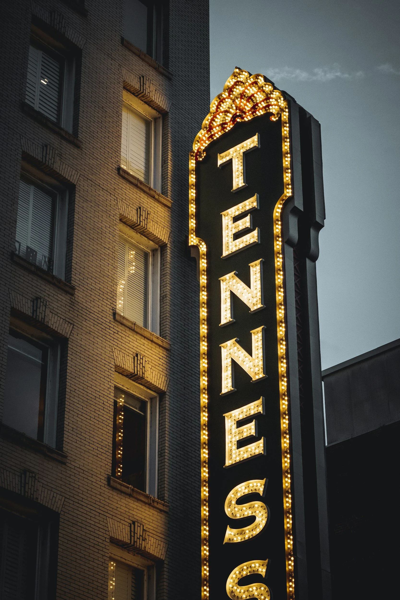 A lit up sign on the side of a brick building that reads "tennesee"