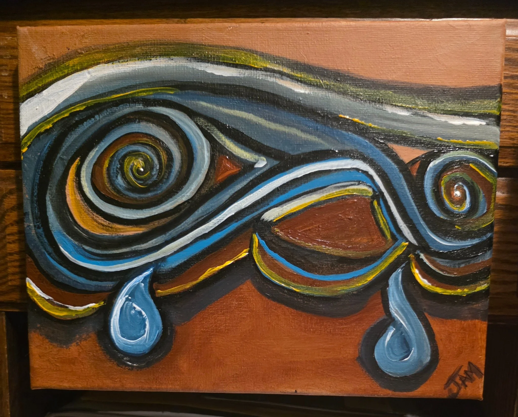 Abstract painting with swirling patterns in shades of blue, black, white, yellow, and green, on a wooden panel background.