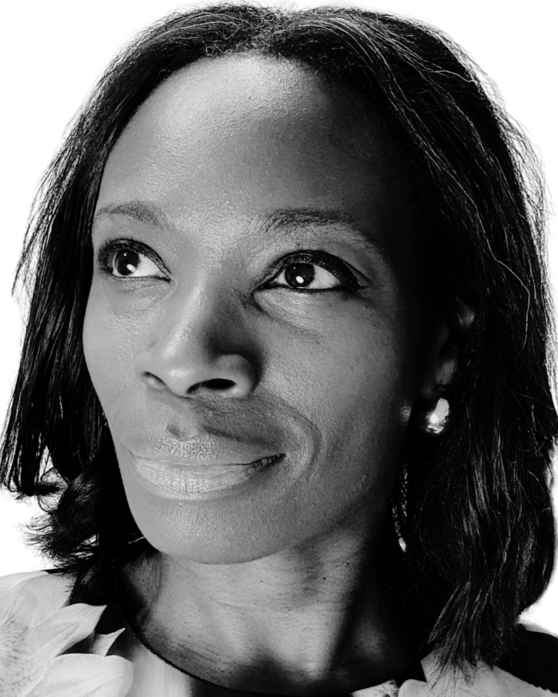Close-up black and white portrait of a woman - Dionne Mallens - with smooth skin, dark hair, and pearl earrings, looking slightly to the side with a gentle smile.