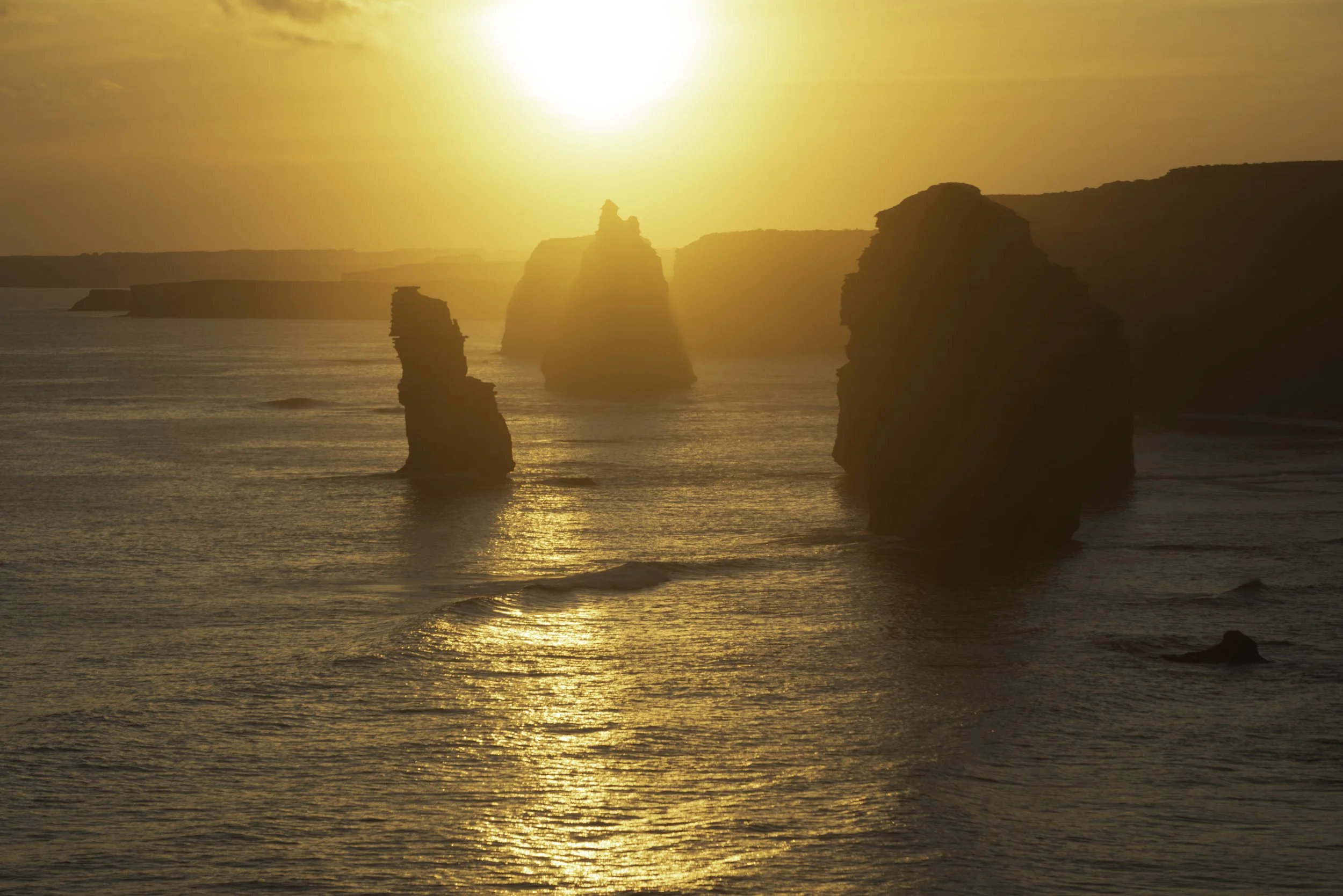 Sunset over the ocean with rocky sea stacks in the foreground.