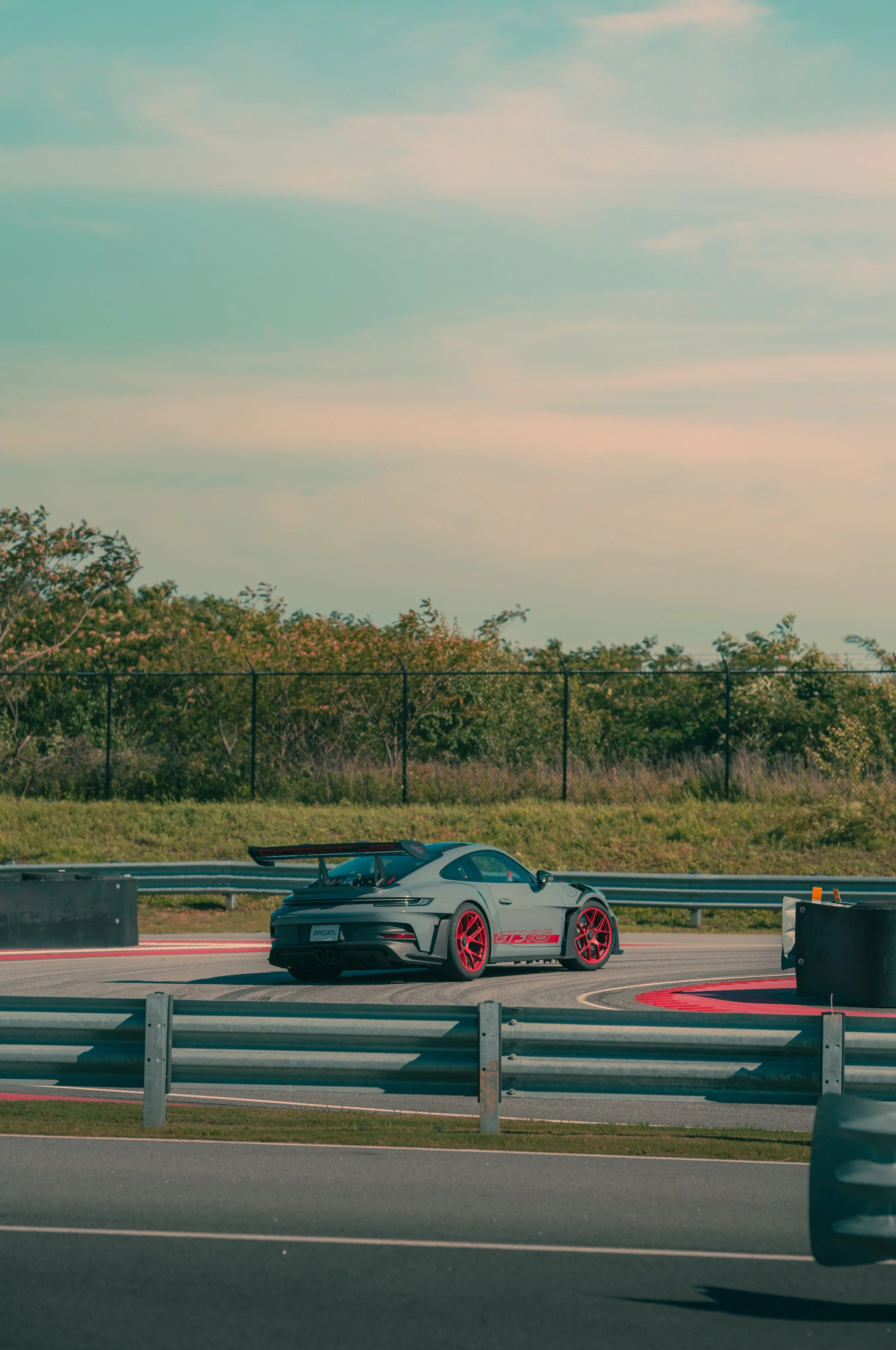 A race car on a race track with a cloudy sky and trees in the background.