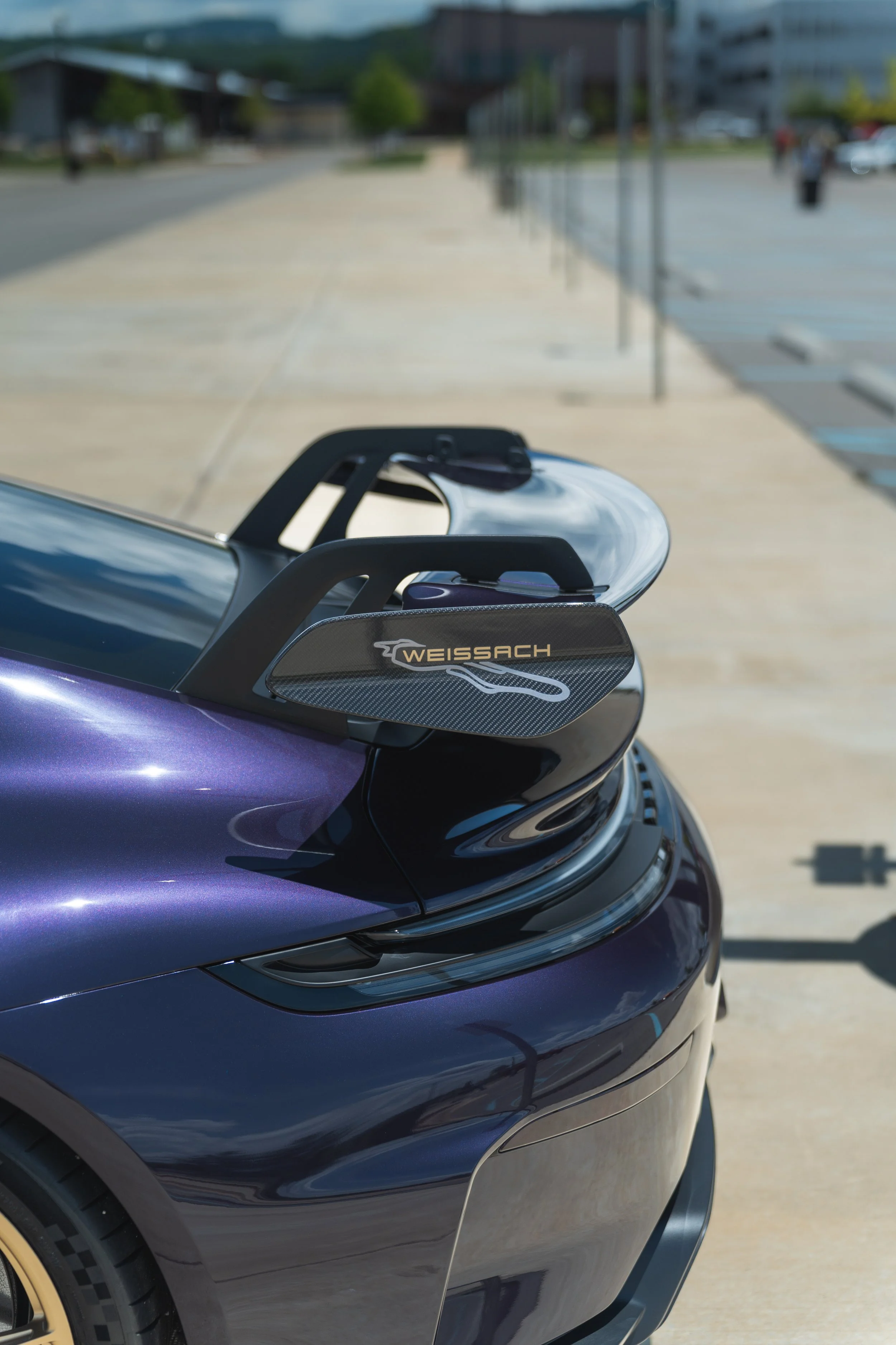 Close-up of a dark blue or purple sleek modern electric vehicle with a roof-mounted display screen and the brand name 'Weissach' on a side panel.