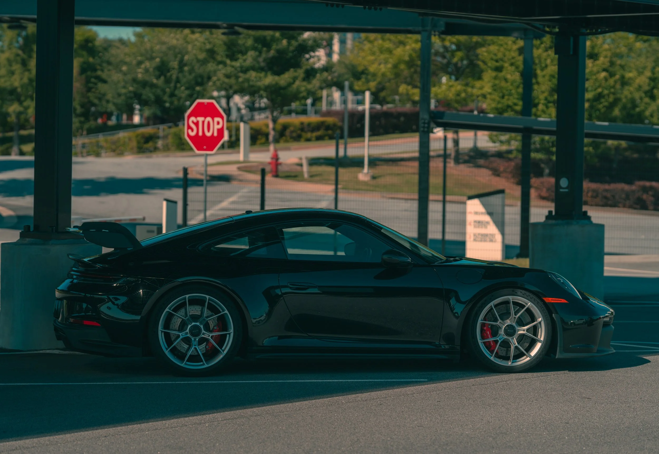 A black sports car parked inside a parking garage with a stop sign visible through the window.