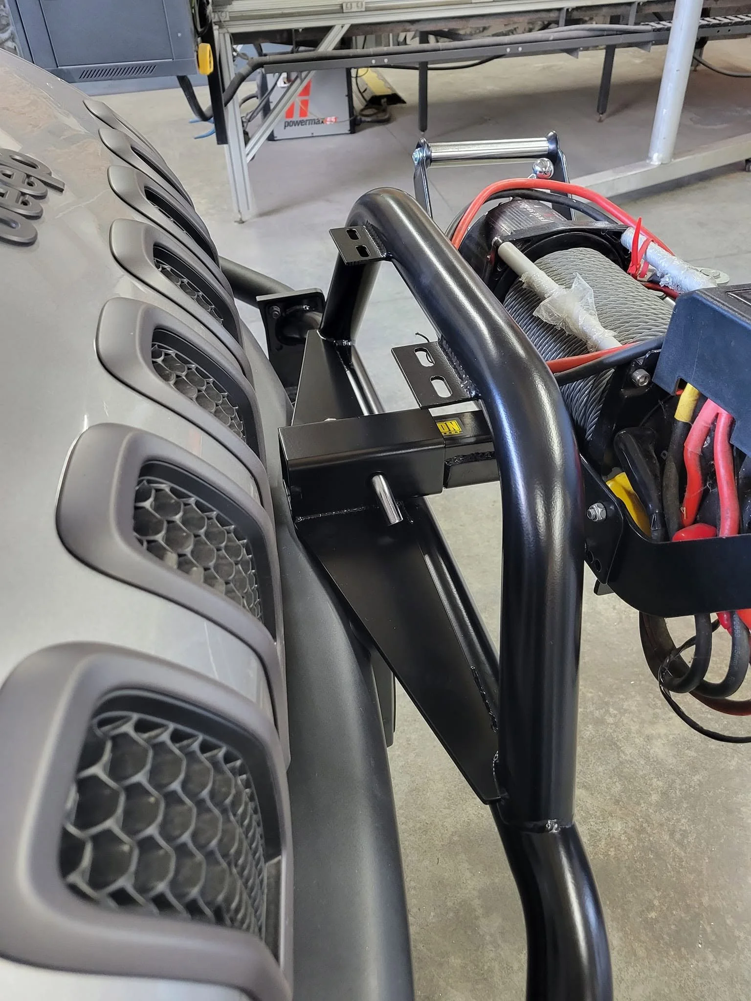 Heavy-duty custom steel winch mount and bumper fabrication installed on an off-road vehicle.