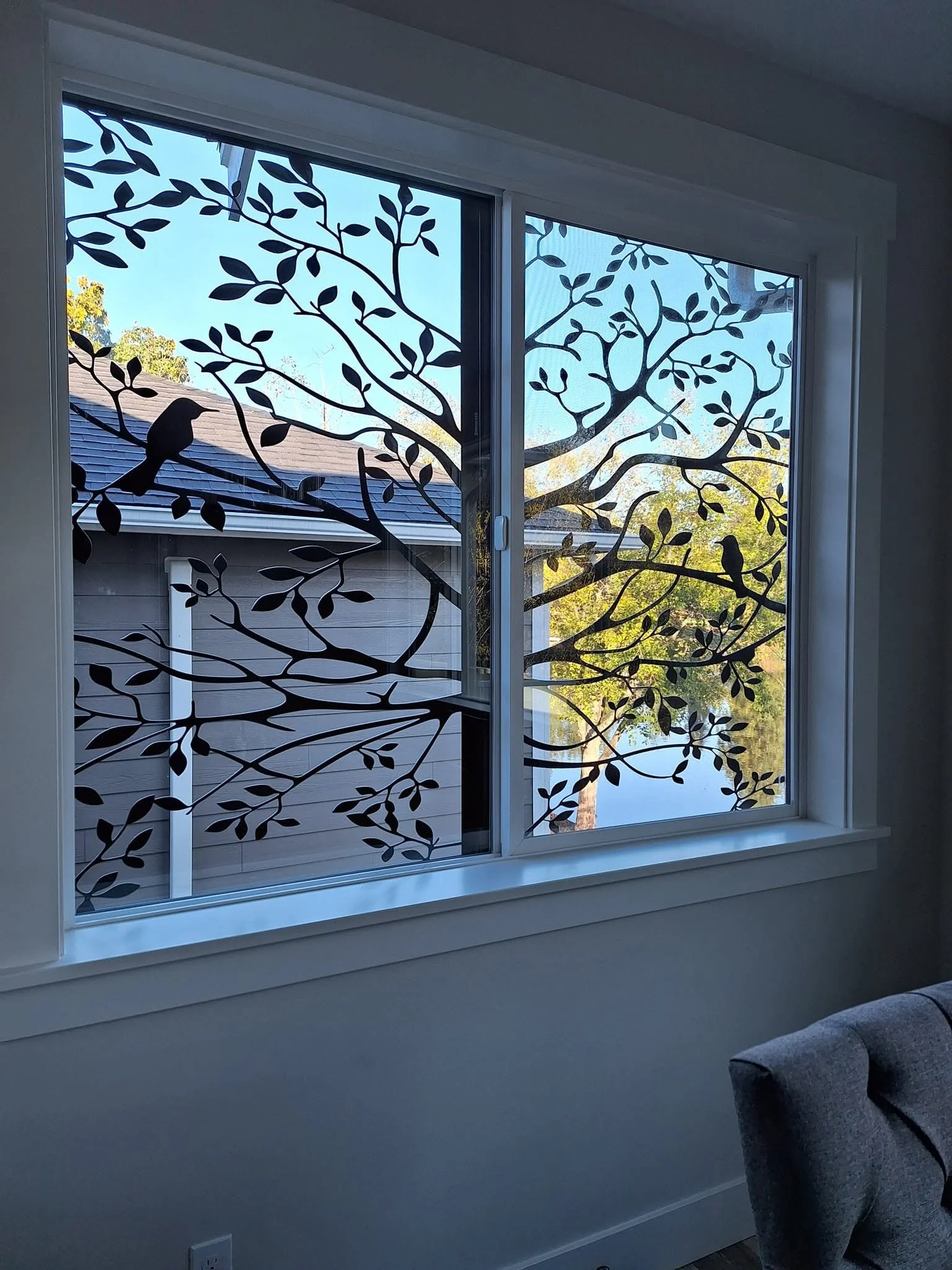 Custom CNC-cut metal window screen featuring a decorative tree branch and bird silhouette design.