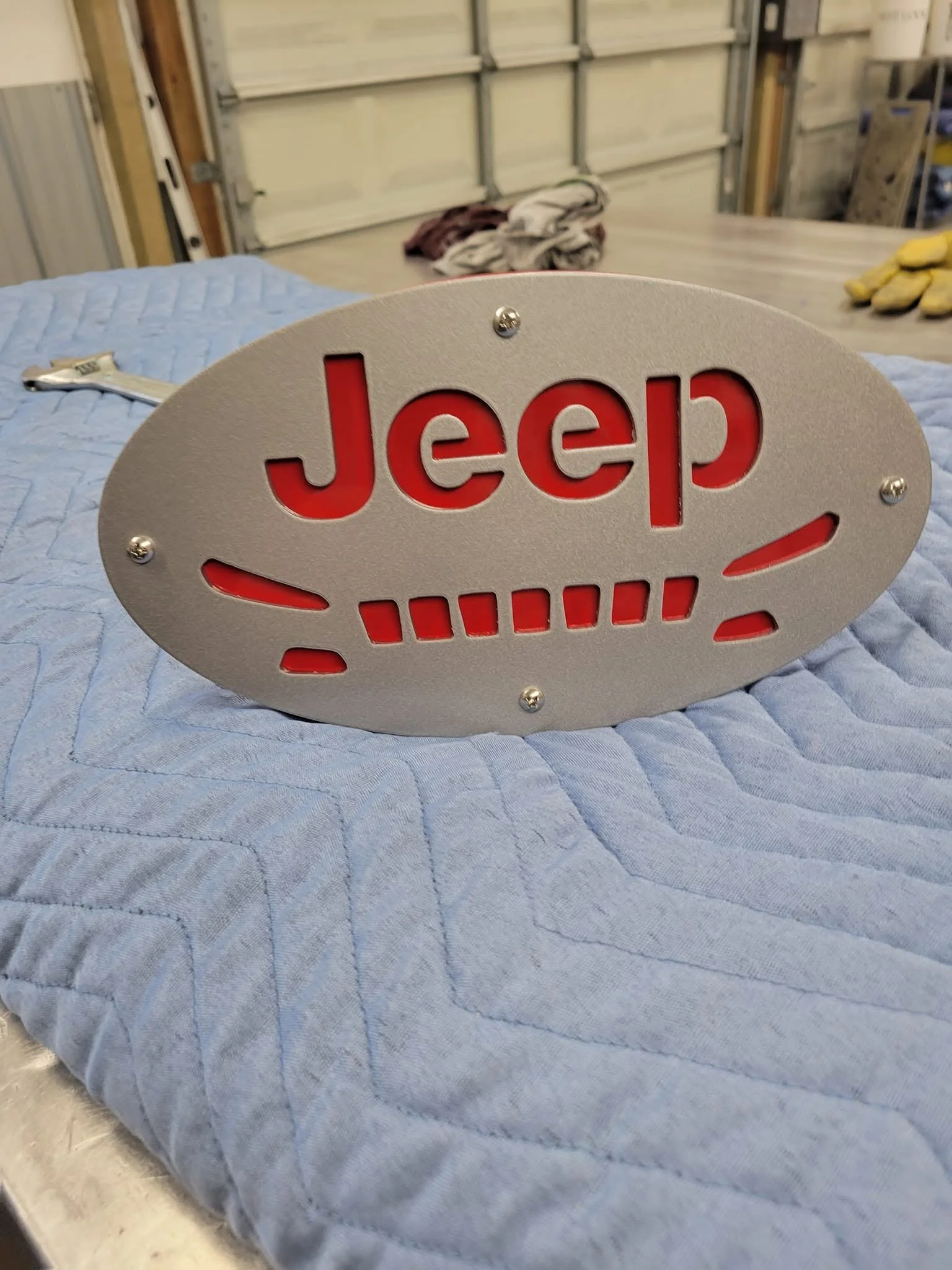 Custom Jeep-branded metal automotive plaque or trim component with precision cut-out design.
