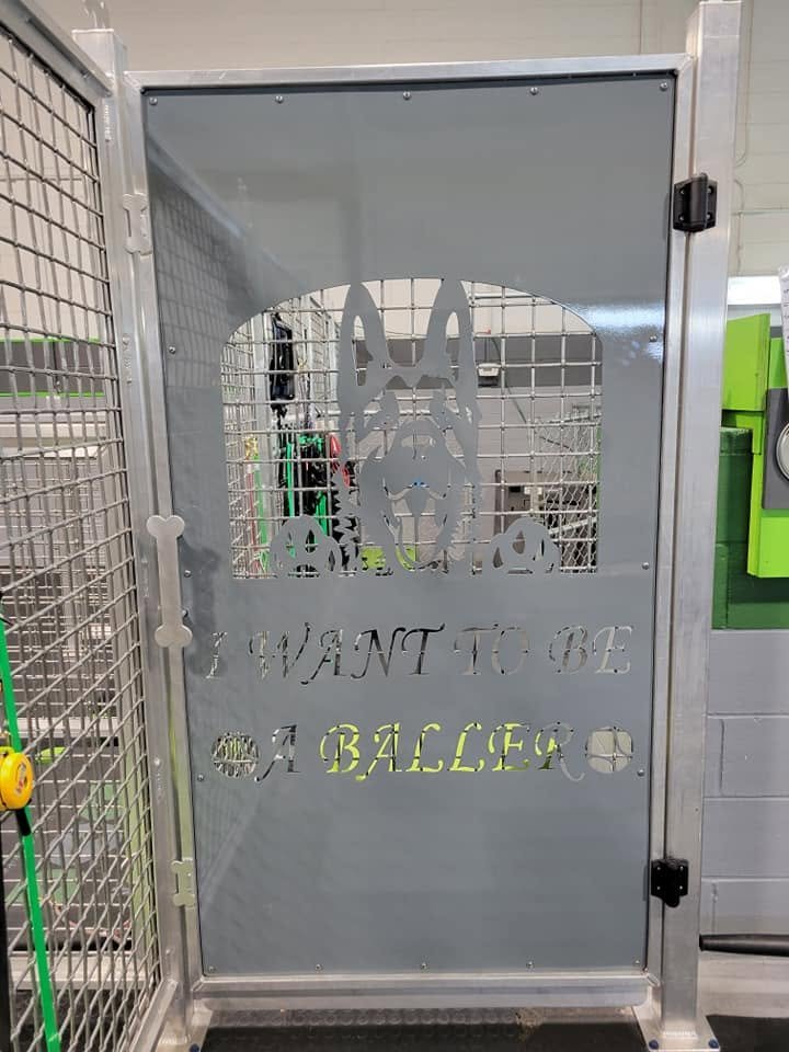 Bespoke CNC-cut metal dog kennel door with custom laser-etched personalization.