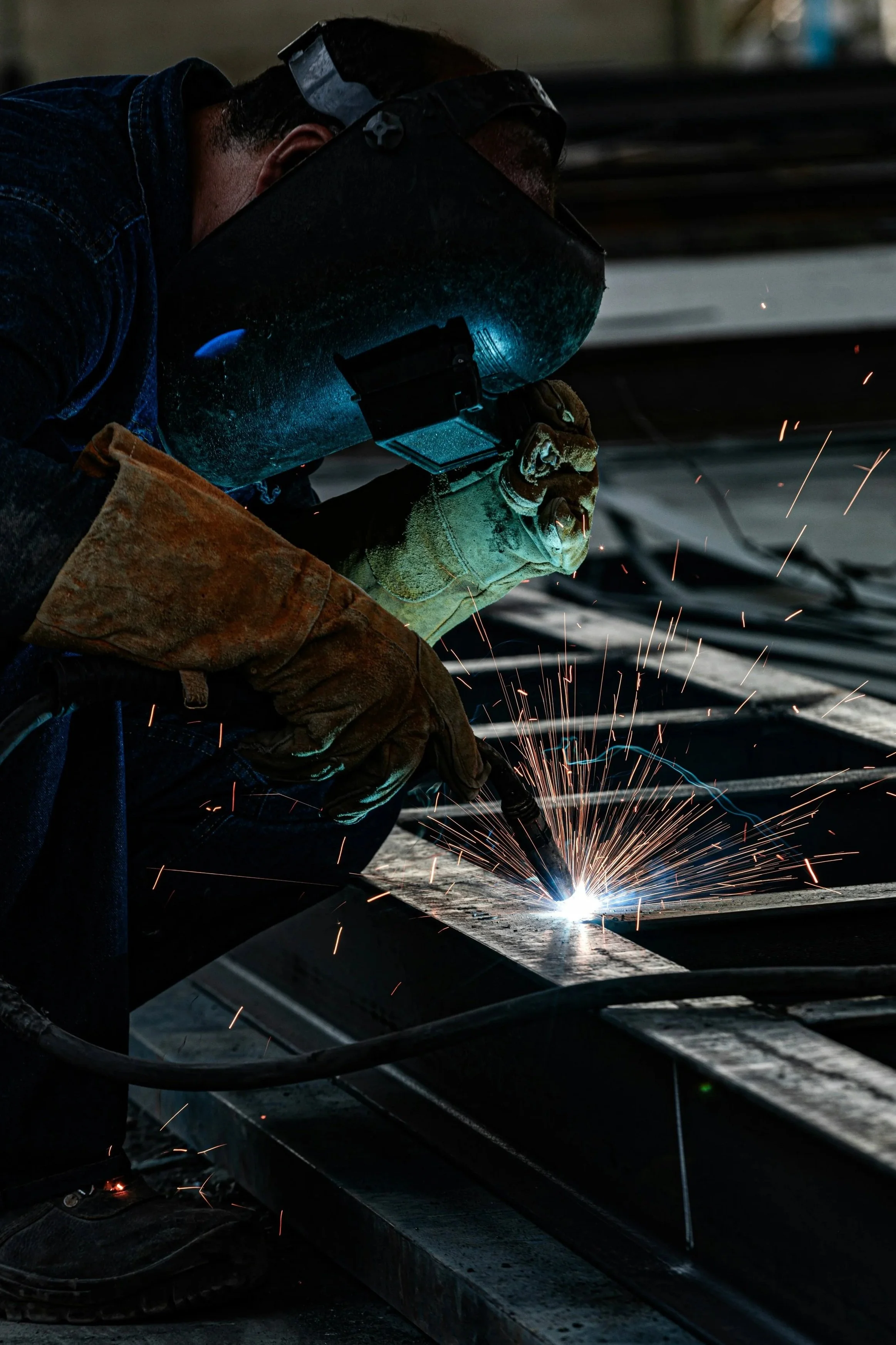 Professional welder performing precision industrial-grade MIG welding on structural steel components for custom fabrication projects.