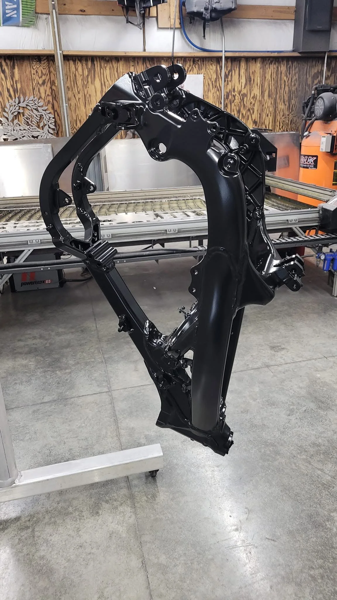 Professional metal fabrication of a motorcycle frame with a clean black powder-coated finish.