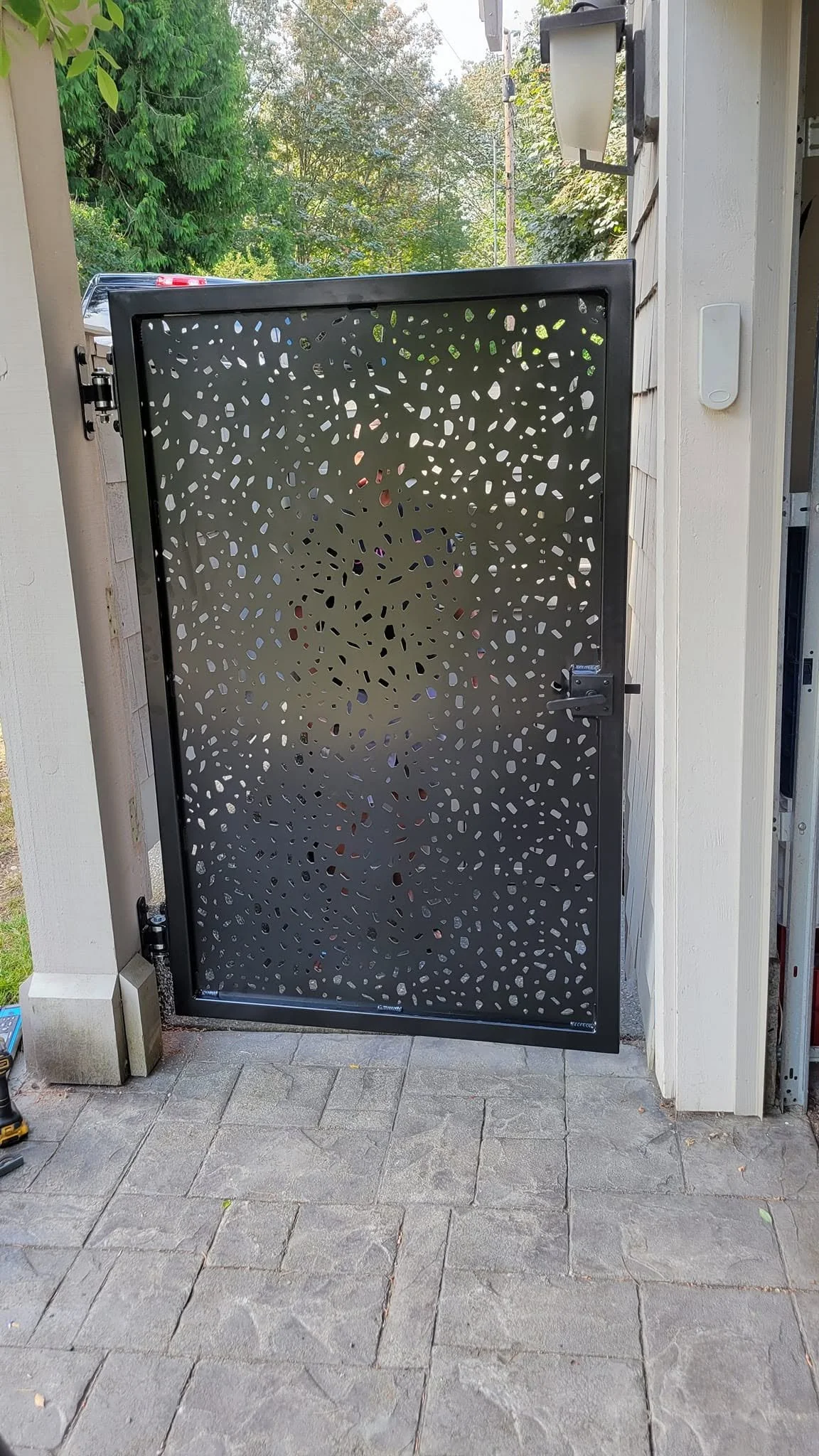Decorative CNC-cut metal privacy screen or gate panel with a modern speckled design.