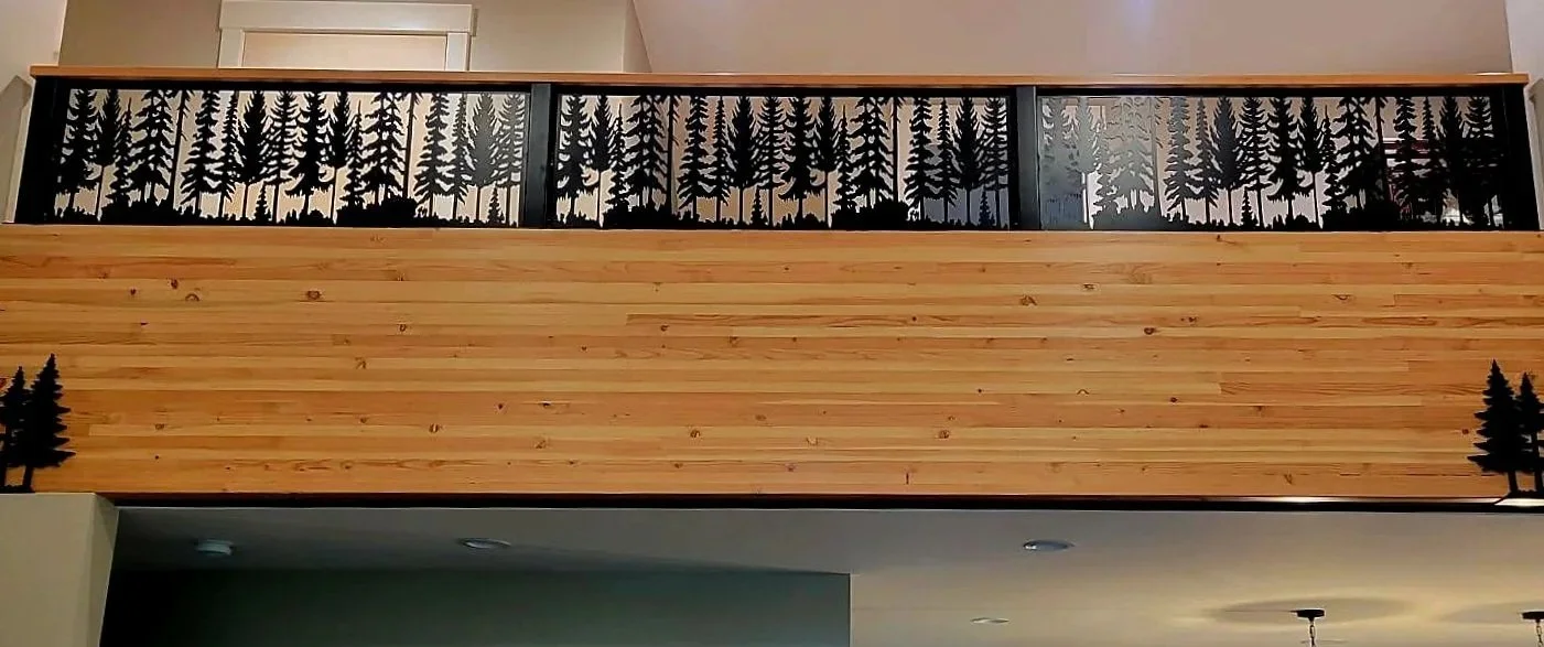 Custom interior metal railing featuring a detailed CNC cut pine forest pattern installed against a wood-paneled wall.