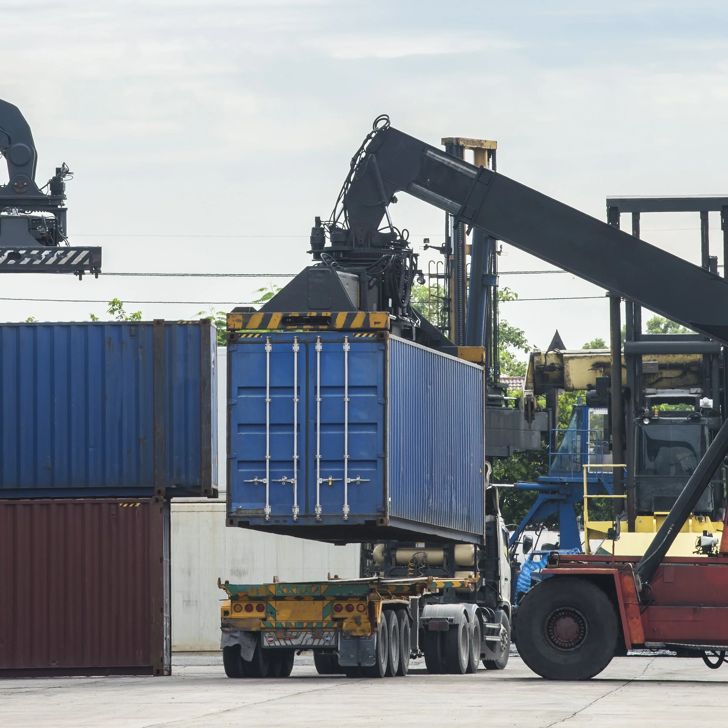 Construction vehicles and equipment are on a construction site or in an industrial area, with a blue shipping container or storage unit in the foreground.