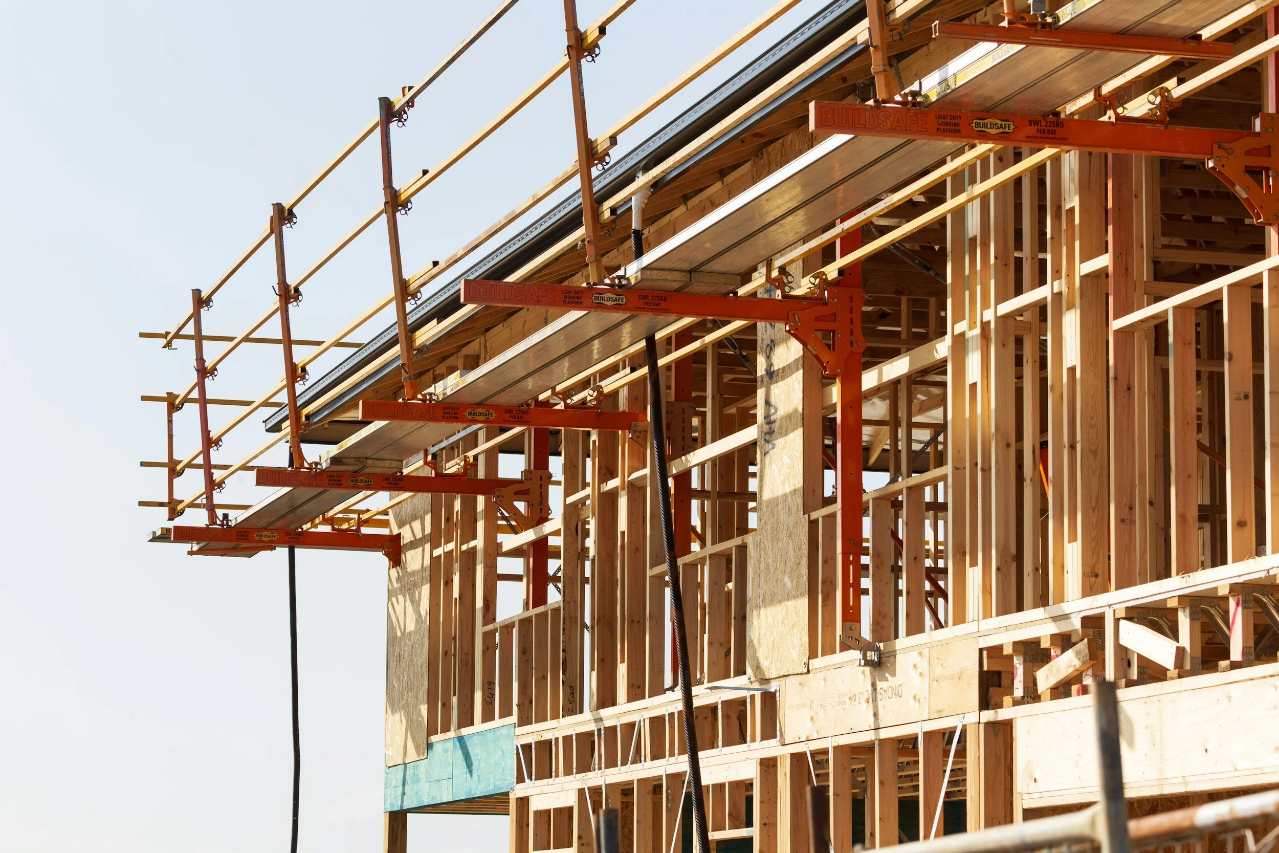 Construction site with wooden framework and orange scaffolding.