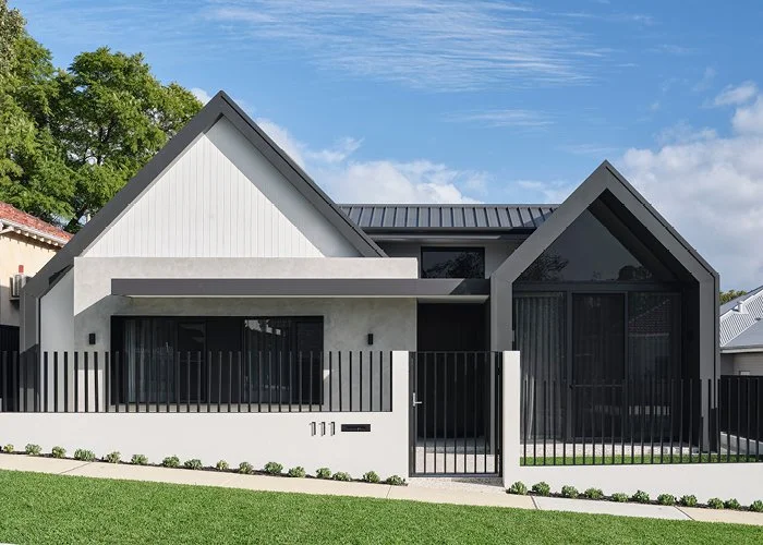 Modern gray house with gabled roof, black fence, and green lawn under blue sky.