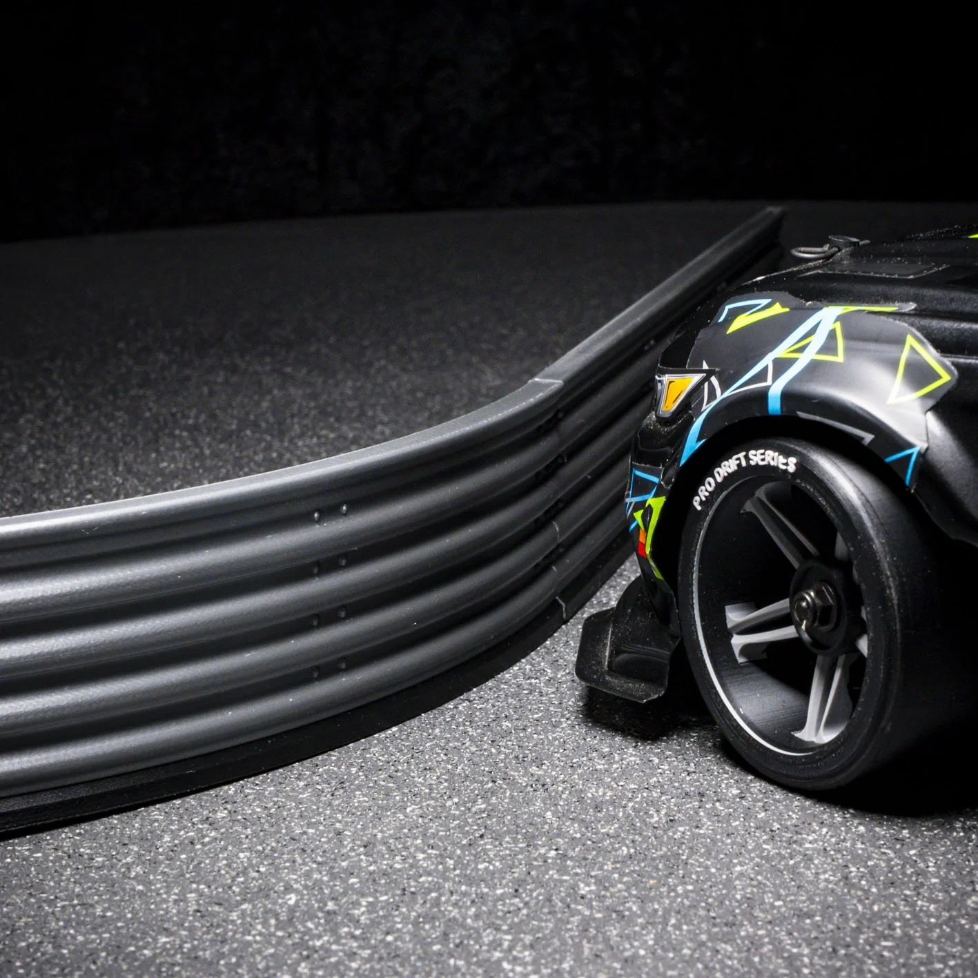 Close-up of a professional drift car tire and a section of a race track with tire barriers.
