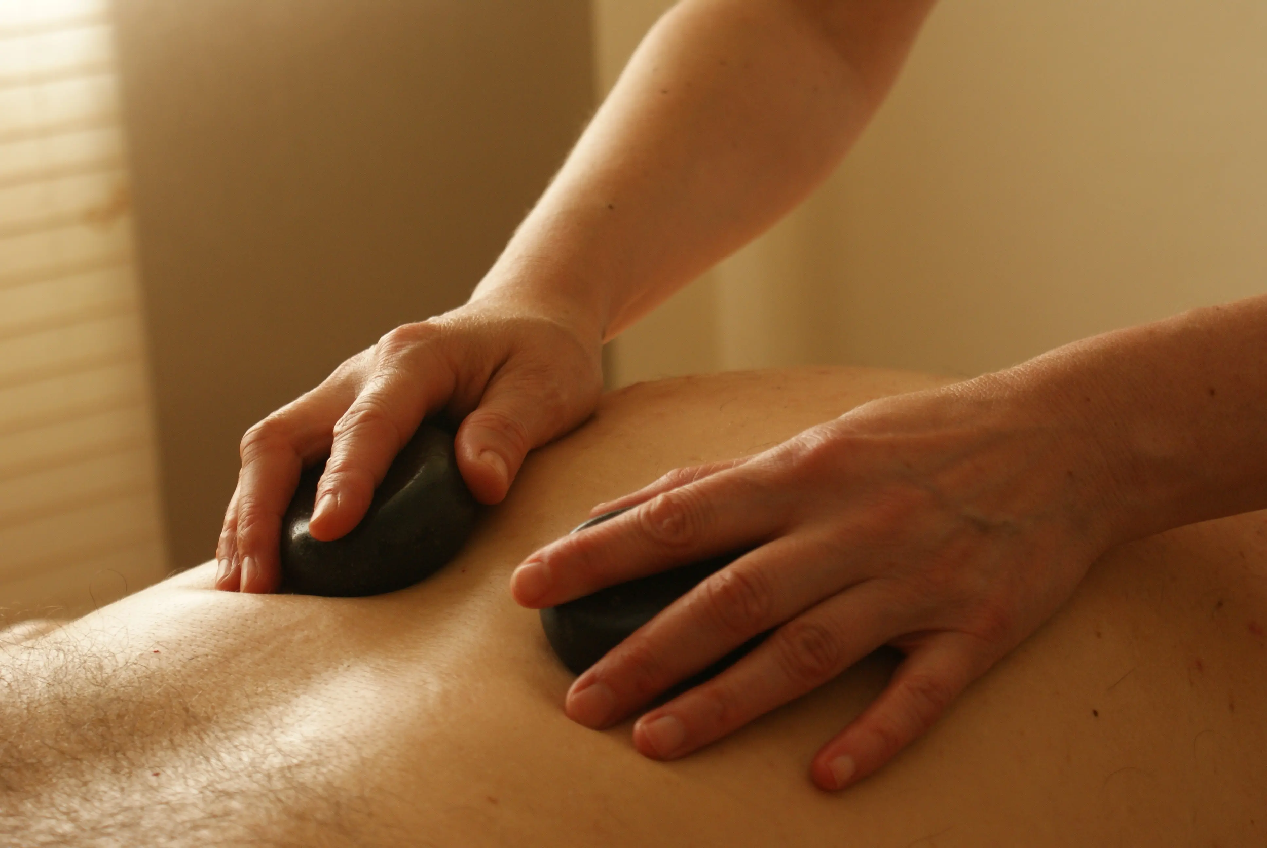Person receiving a massage with hands applying pressure on their back.