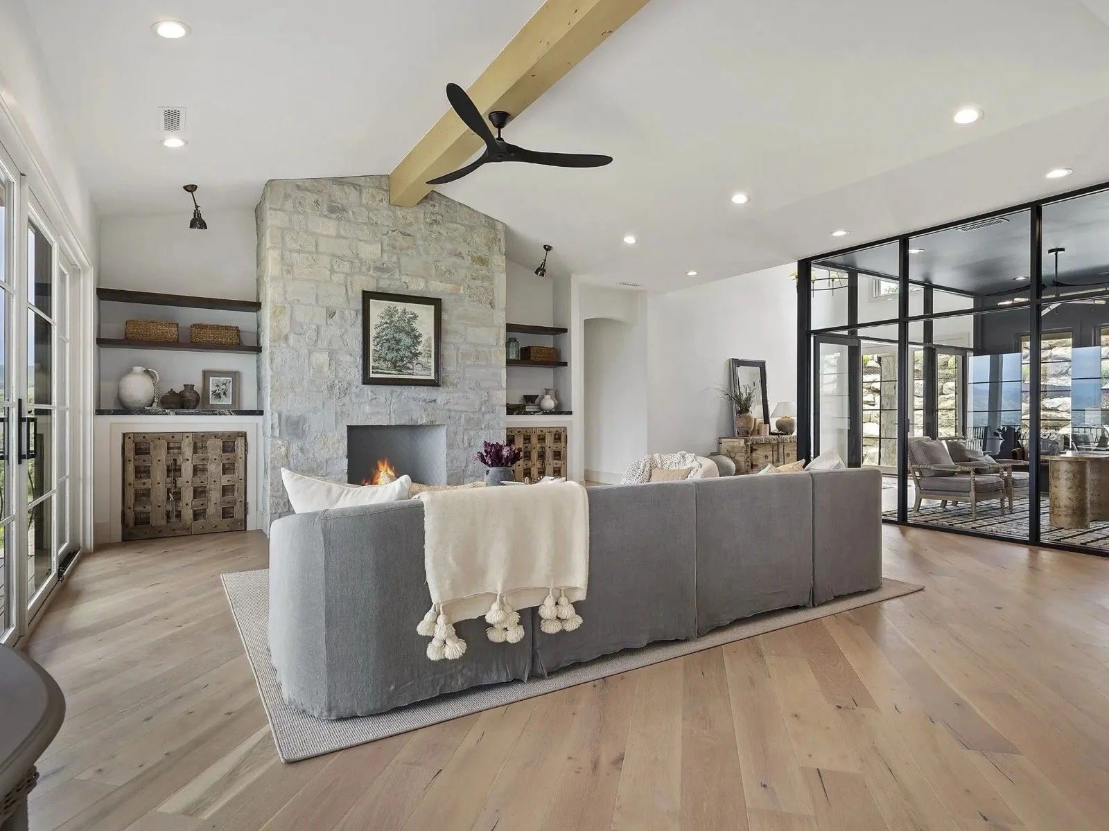 transitional-mountain-home-family-room-stone-fireplace-glass-wall-03.jpeg