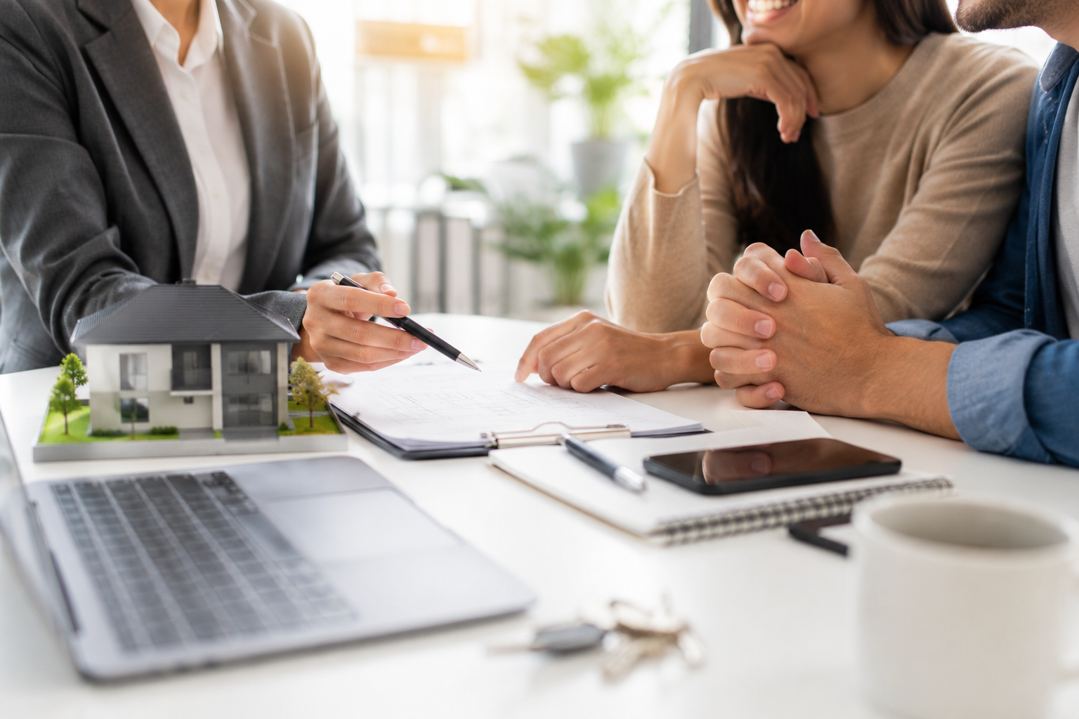 Real estate agent showing house plans to a couple during a meeting.