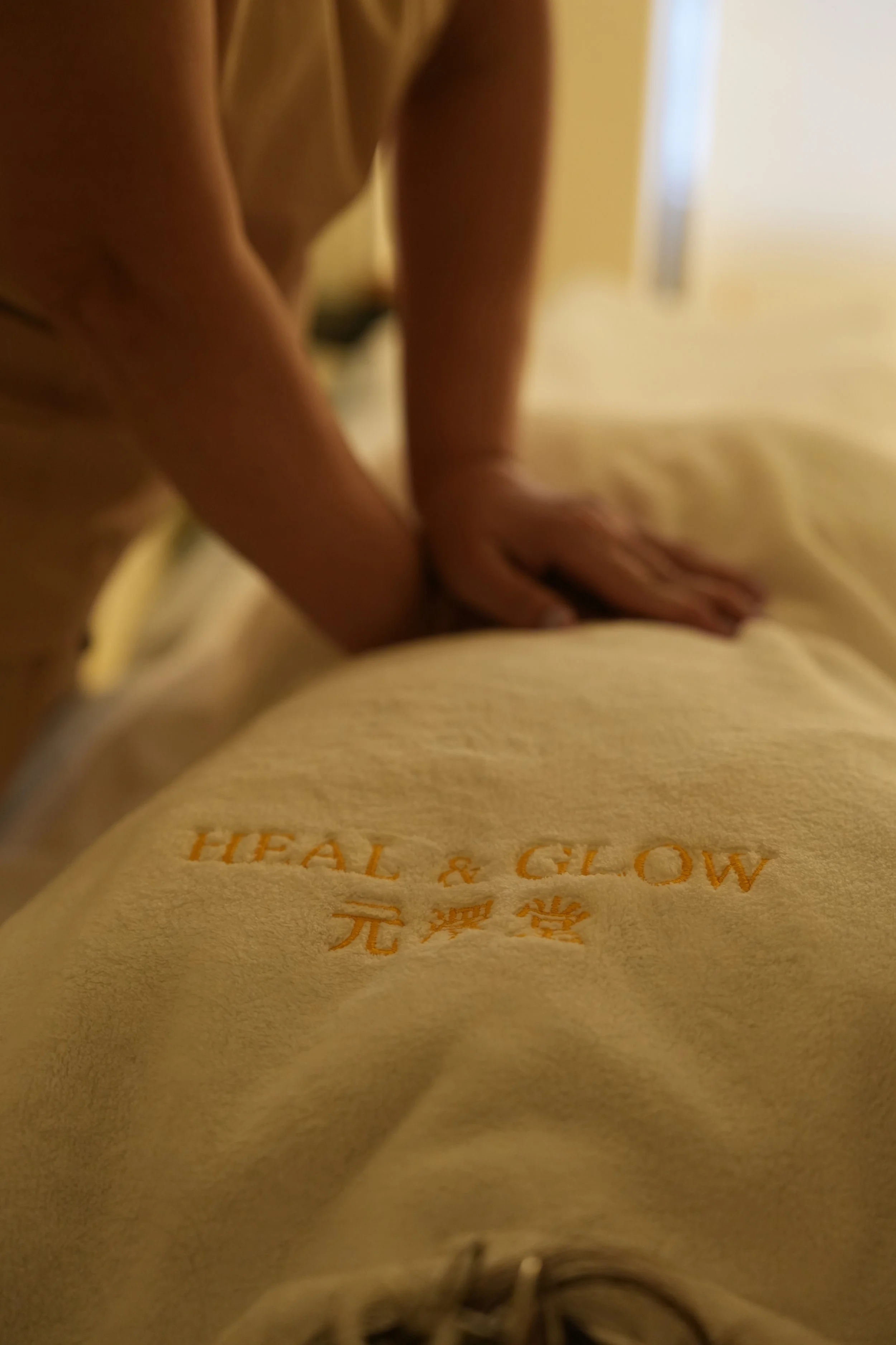 Close-up of a yellow towel with orange embroidered text that reads 'HEALTH & GLOW' along with Chinese characters.