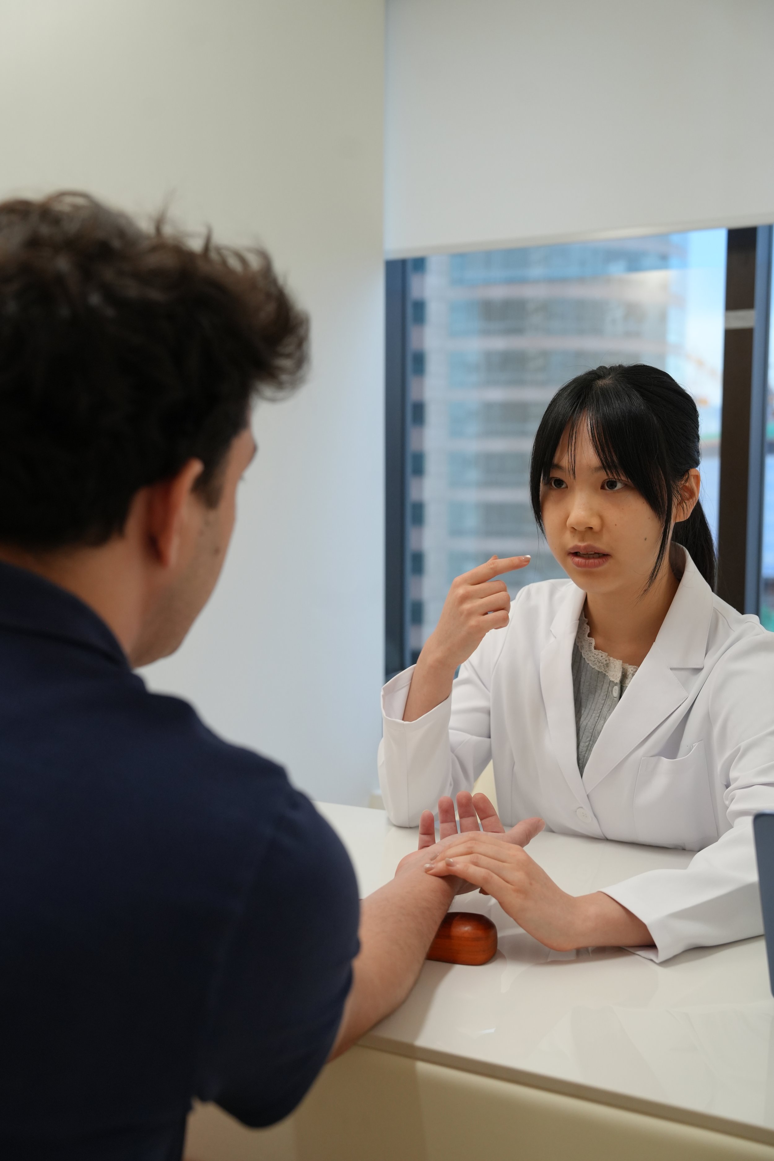 Medical professional examining a woman's shoulder in a clinical setting.