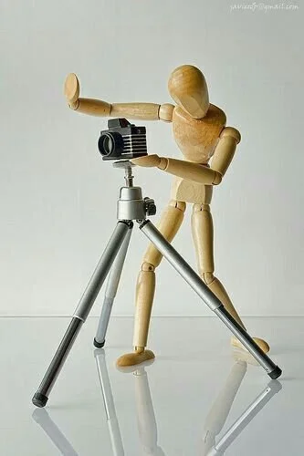 Una figura di legno shoggin e una macchina fotografica su un treppiede.