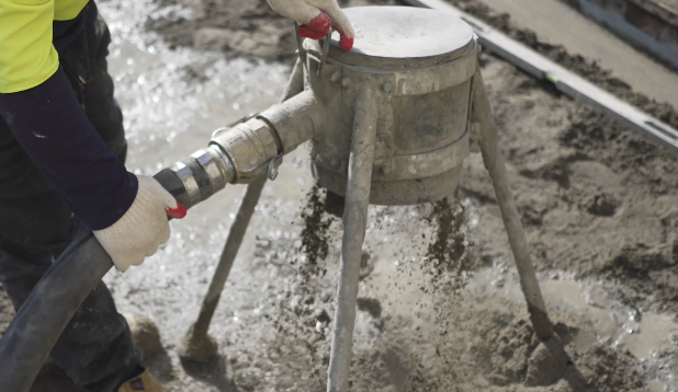 Person using equipment to spread concrete or a similar material on a construction site.