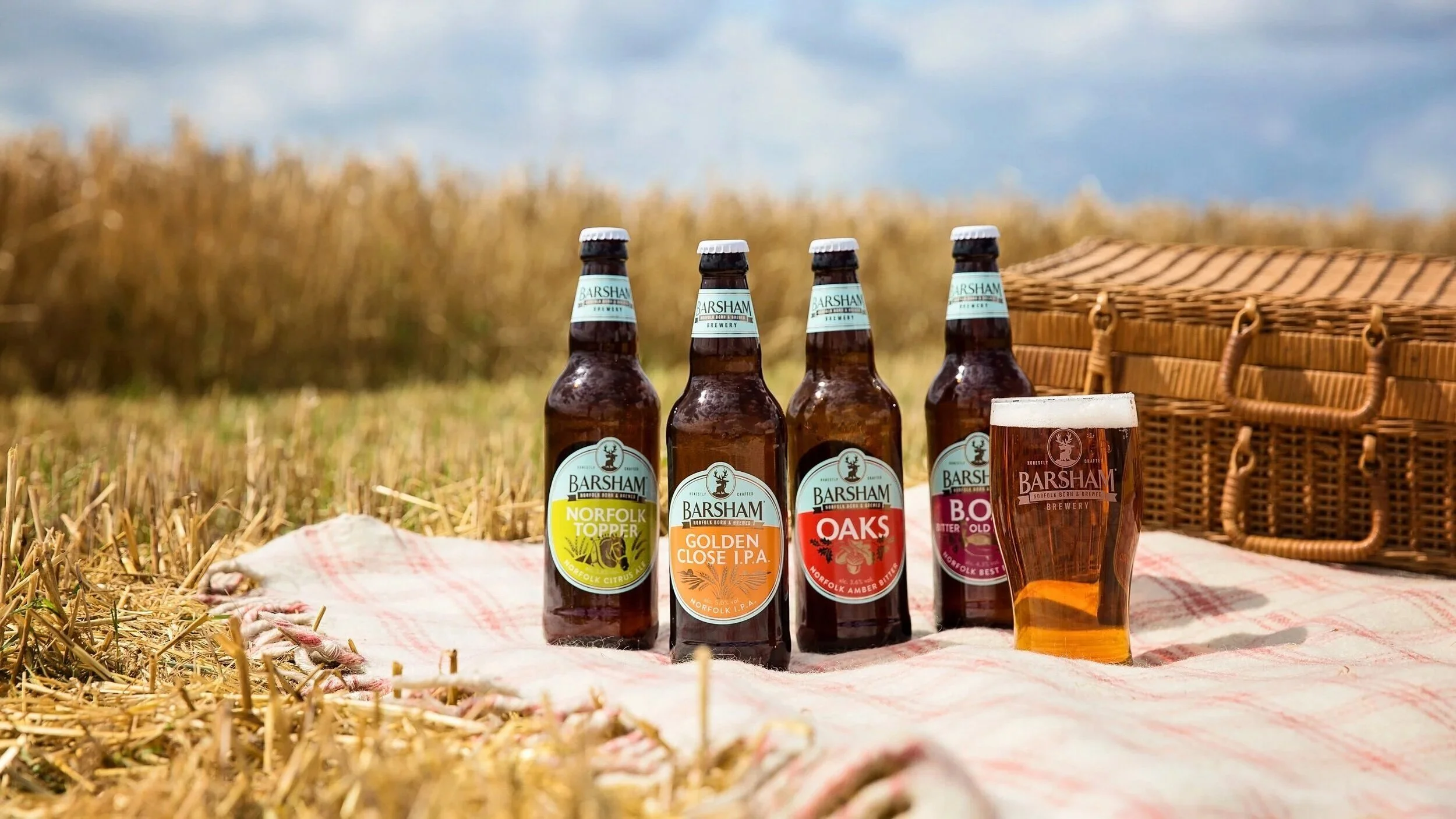 Barsham brewery beers on a picnic blanket in a barley field at harvest time