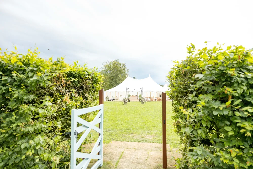 Looking out from Meadow House's garden to the marquee meadow on a wedding day