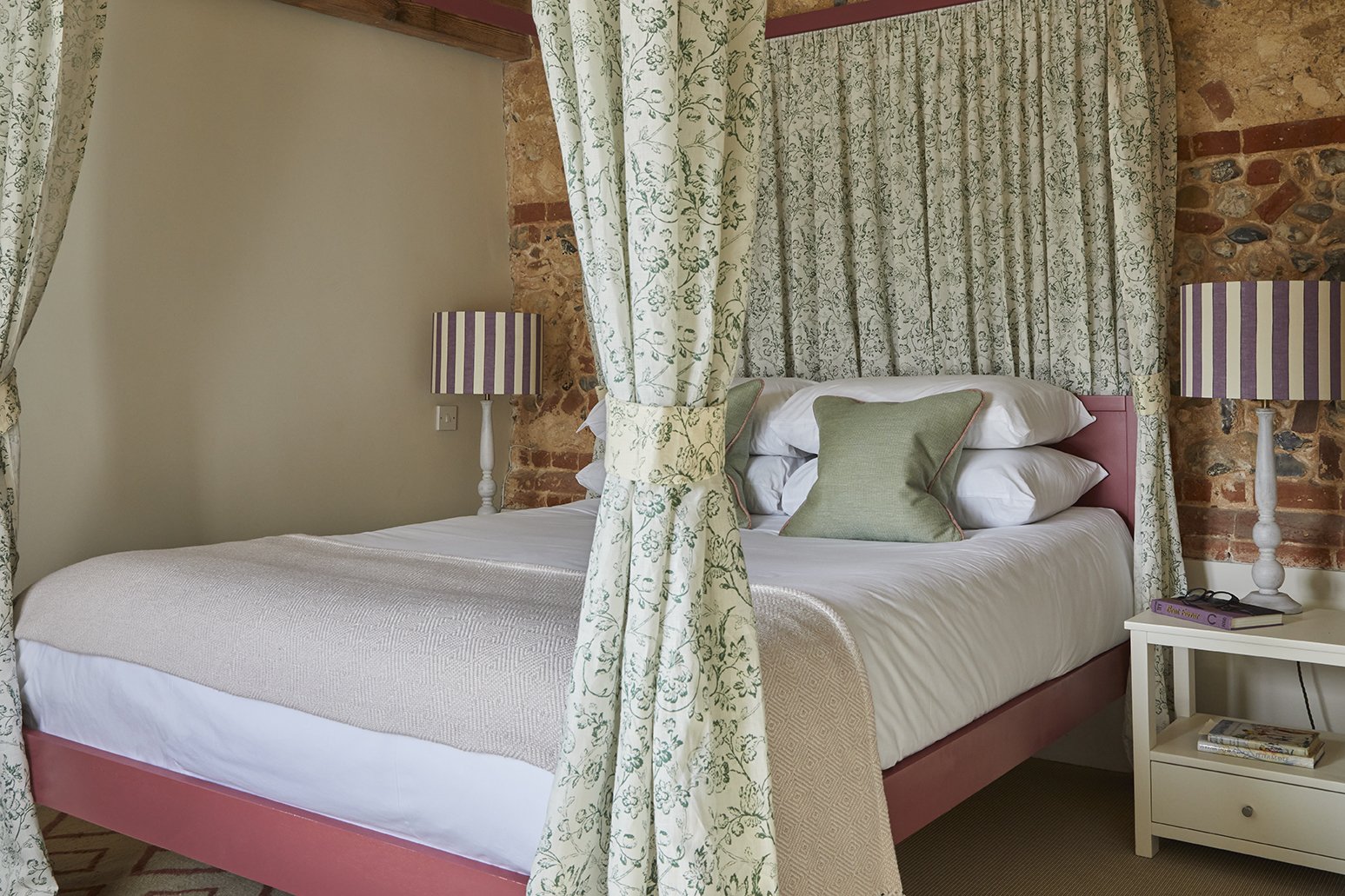 The elegant master bedroom in Little Barsham with a four poster bed hung with curtains in Flora Soames fabrics