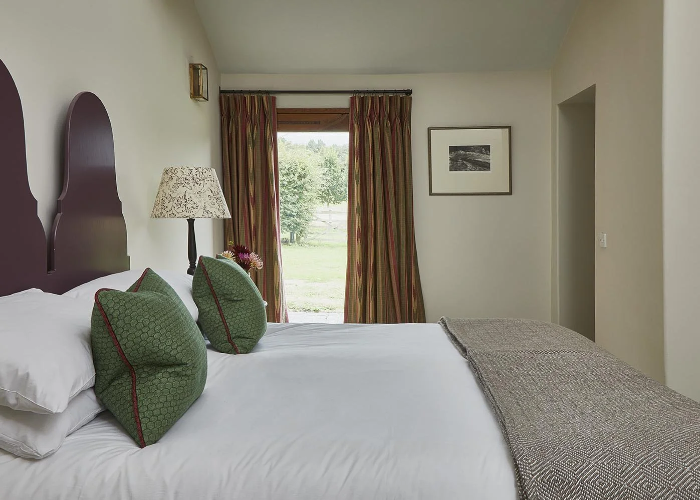 An airy and spacious double bedroom with feature headboard and a door out to the garden