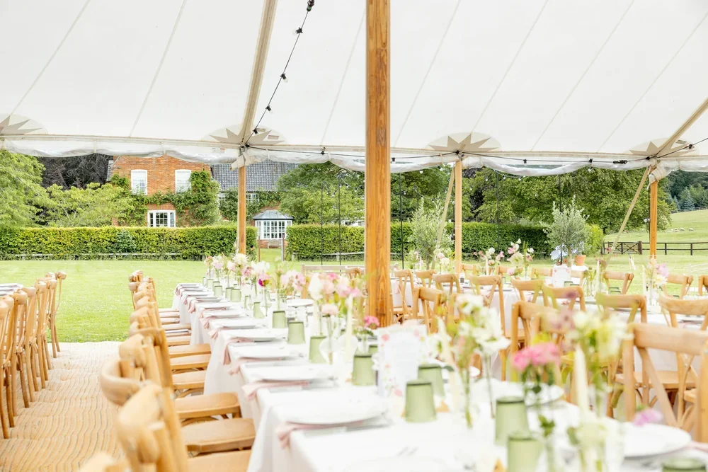 A traditional sailcloth marquee in the meadow adjacent to Meadow House for a wedding