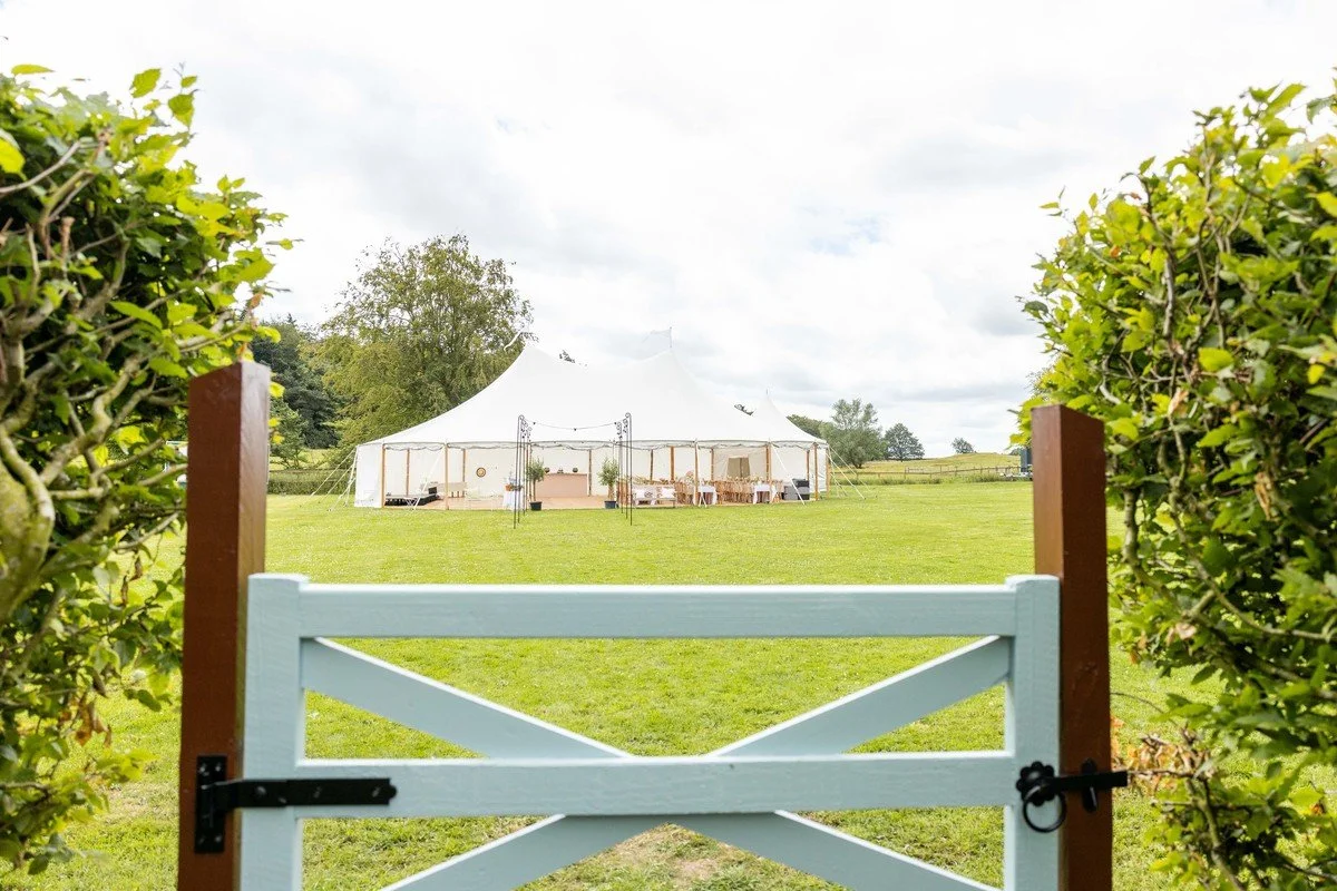Looking out from Meadow House's garden to the marquee meadow on a wedding day
