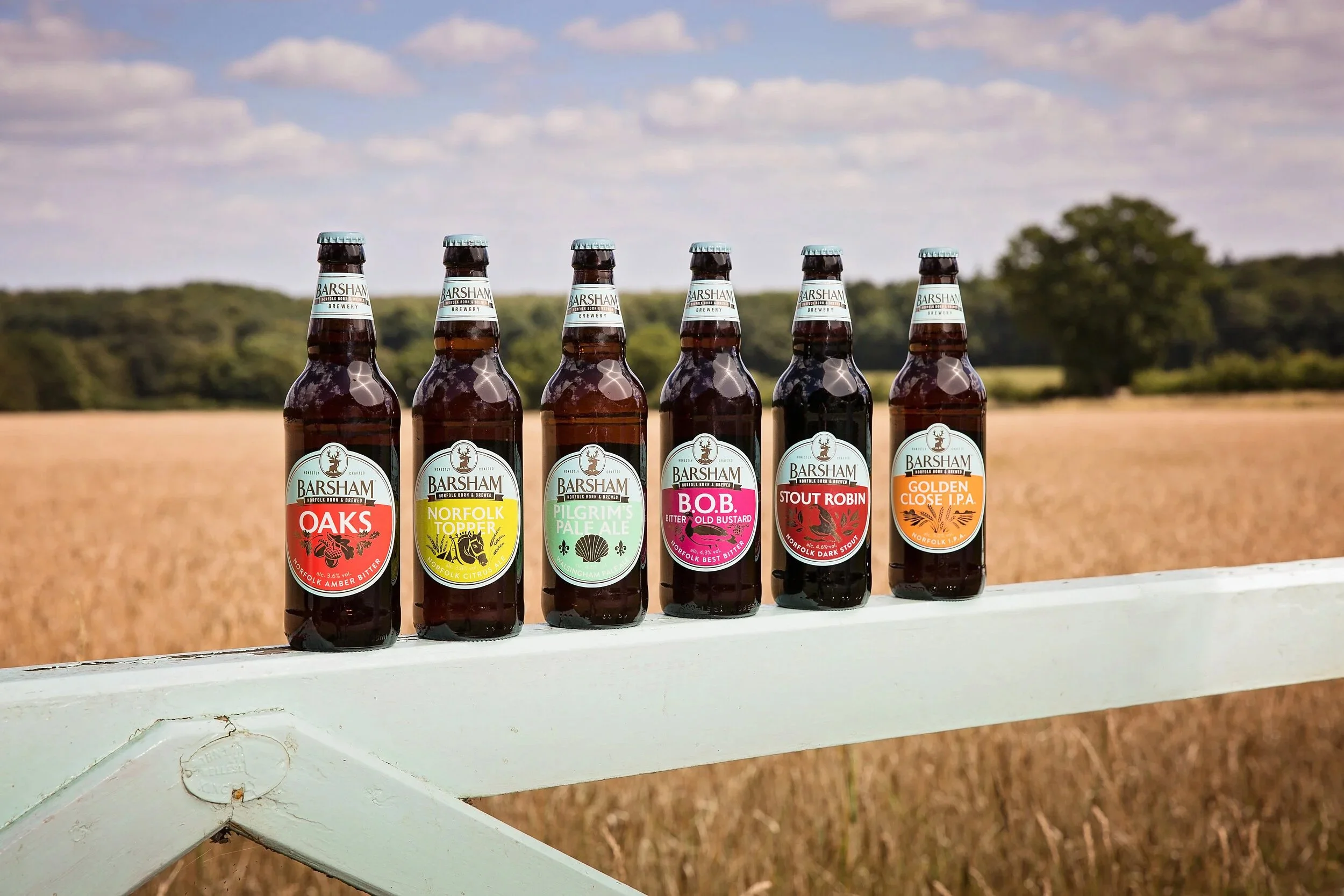Barsham Brewery's beer collection on a farm gate adjacent to a barley field