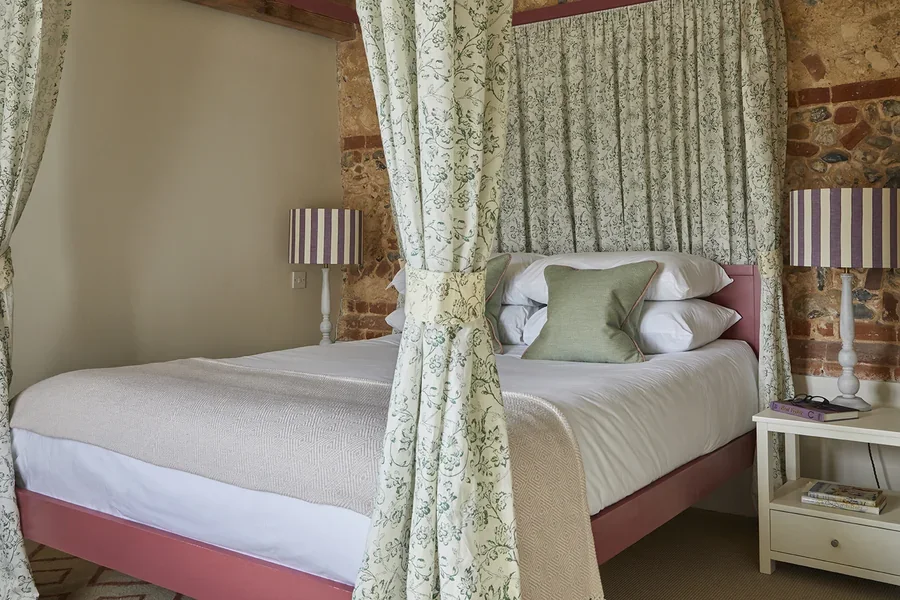 The elegant master bedroom in Little Barsham with a four poster bed hung with curtains in Flora Soames fabrics
