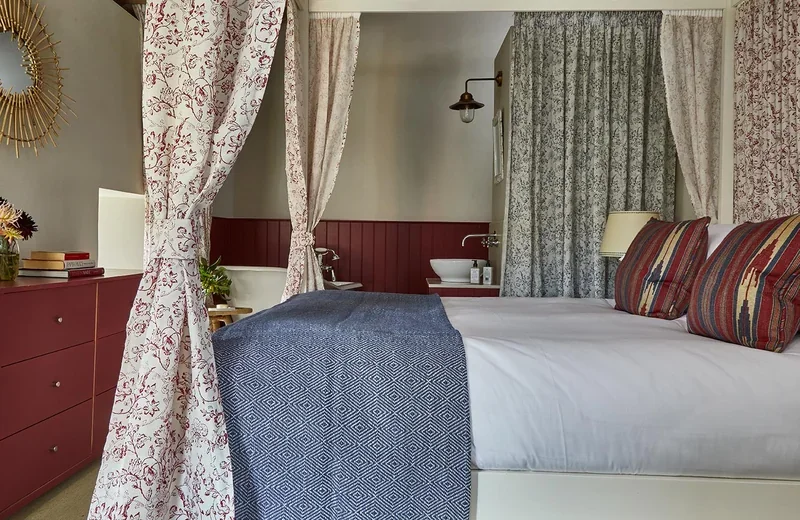 Great East's main bedroom with a four poster bed and roll top bath