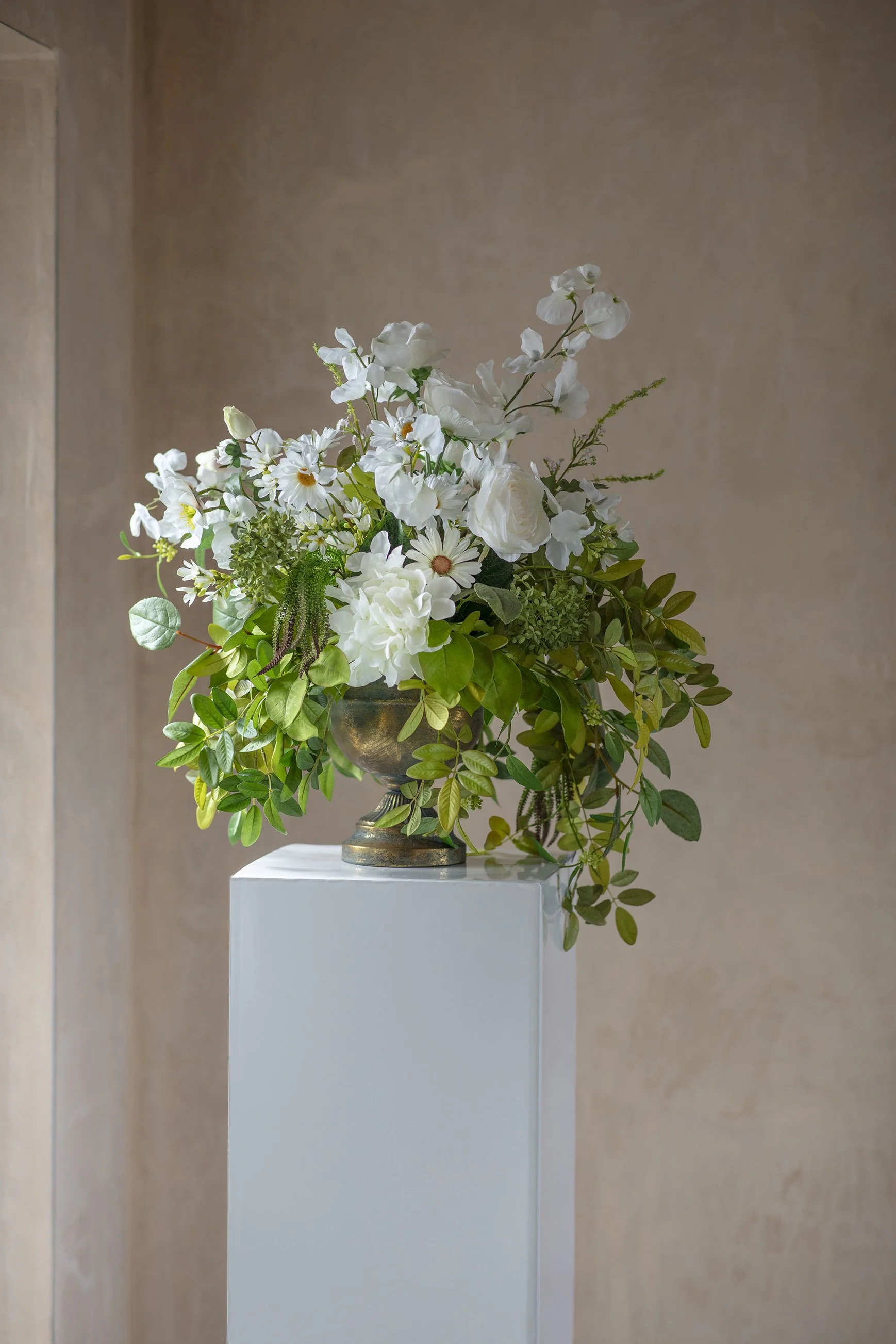 wild white small urn on indoor plinth