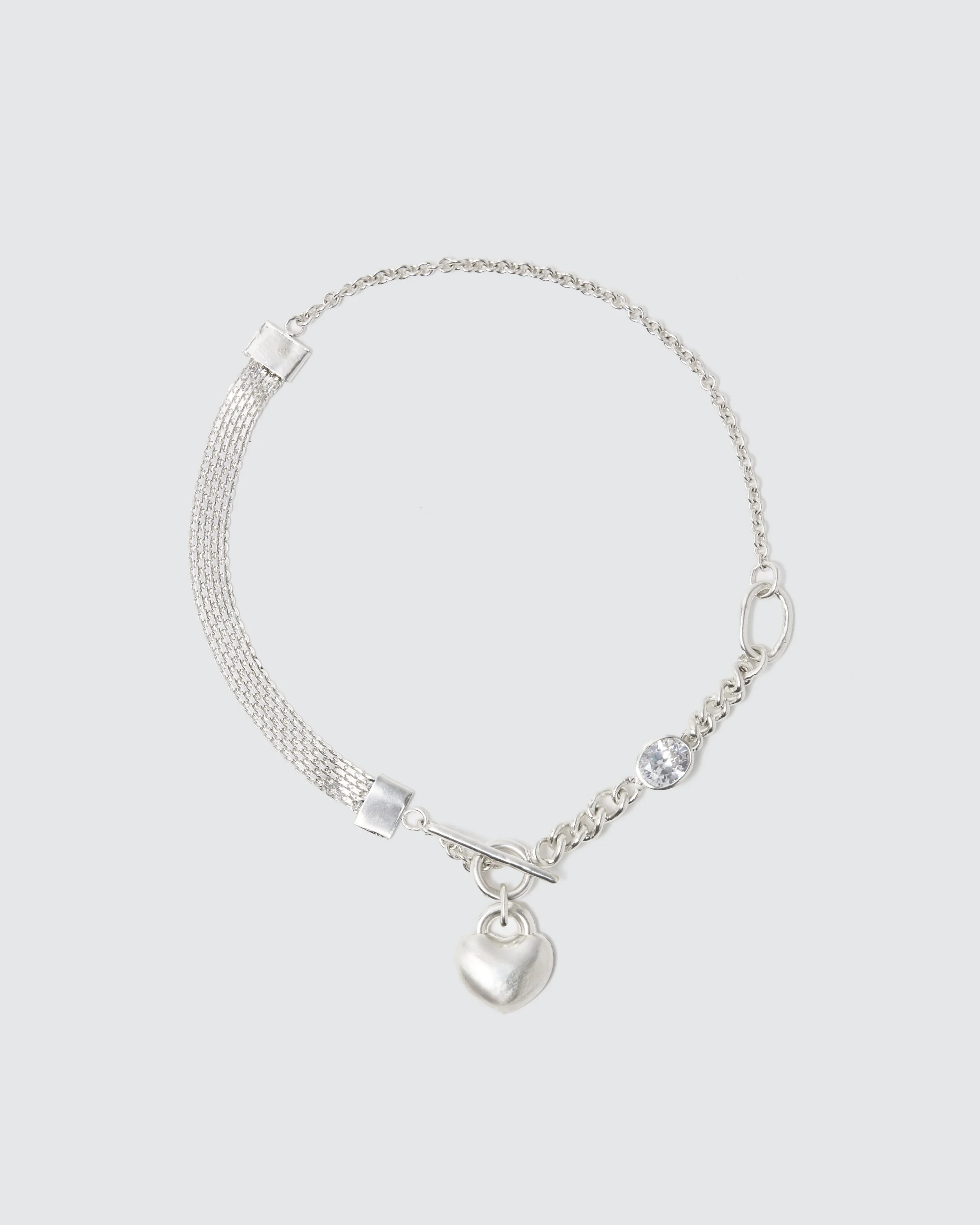 Silver necklace with a heart-shaped pendant and a large clear gemstone, on a light gray background.