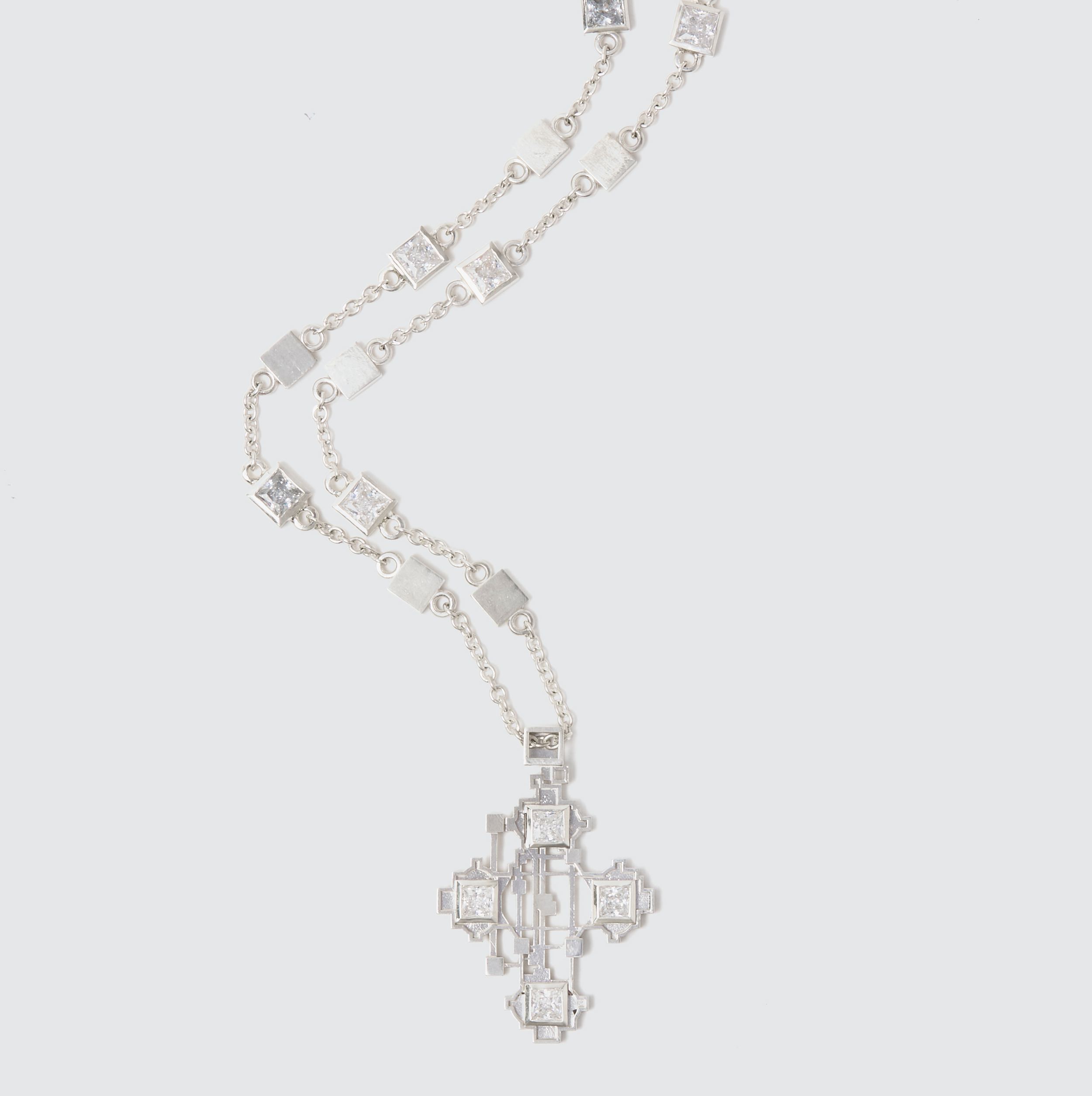 Silver necklace and earrings with geometric patterns and embedded stones arranged on a light gray background.